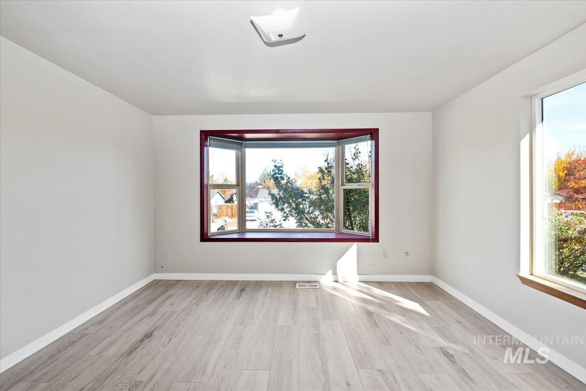 Spare room featuring light wood-type flooring and plenty of natural light