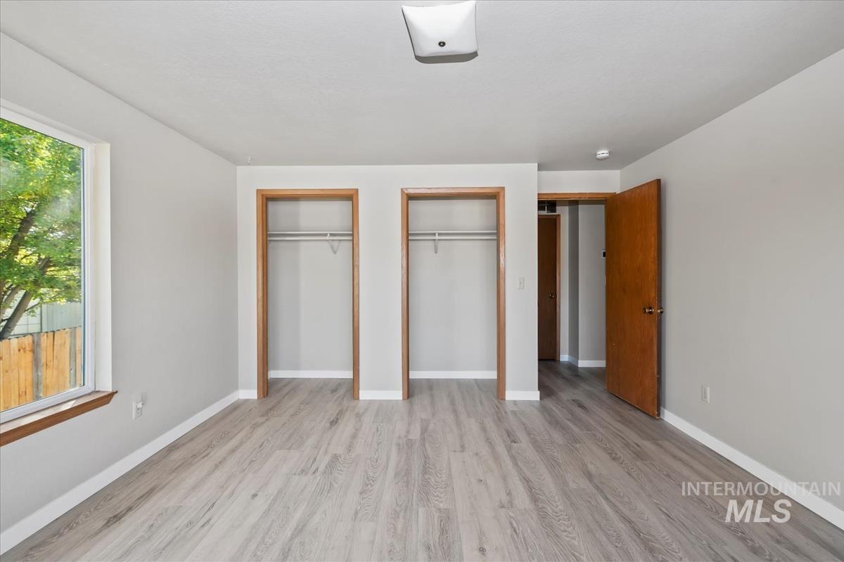 Unfurnished bedroom with two closets and light wood-type flooring