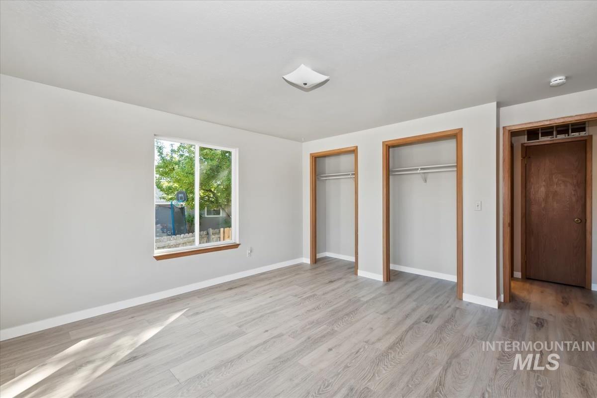Unfurnished bedroom featuring multiple closets and light wood-type flooring