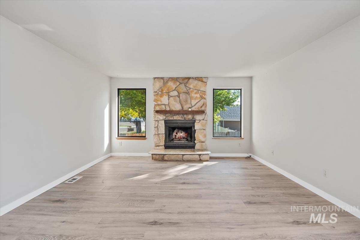 Unfurnished living room with light wood-style flooring and a stone fireplace