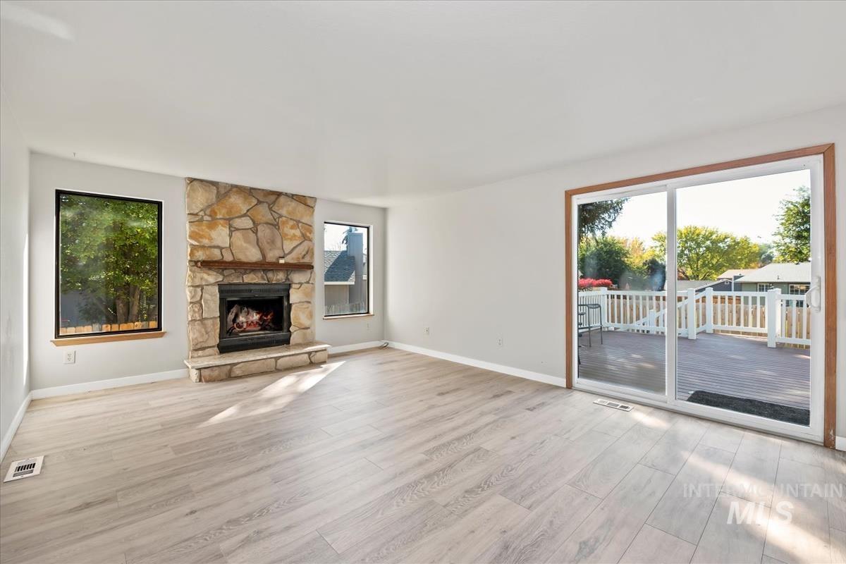 Unfurnished living room with light wood-style floors, plenty of natural light, and a fireplace