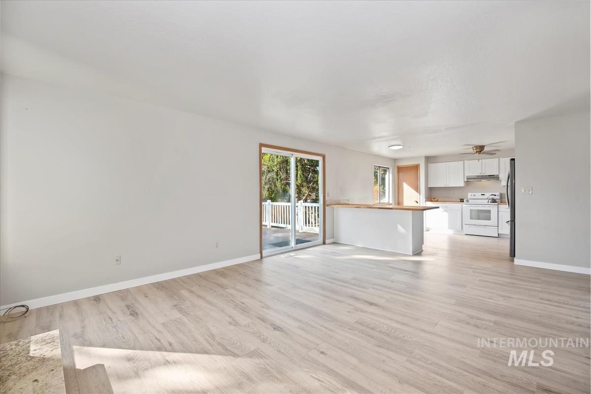 Unfurnished living room featuring baseboards and light wood-type flooring