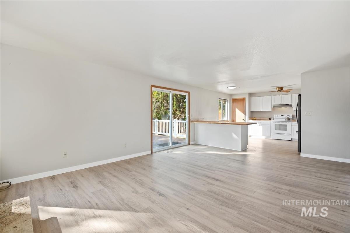 Unfurnished living room featuring baseboards and light wood finished floors