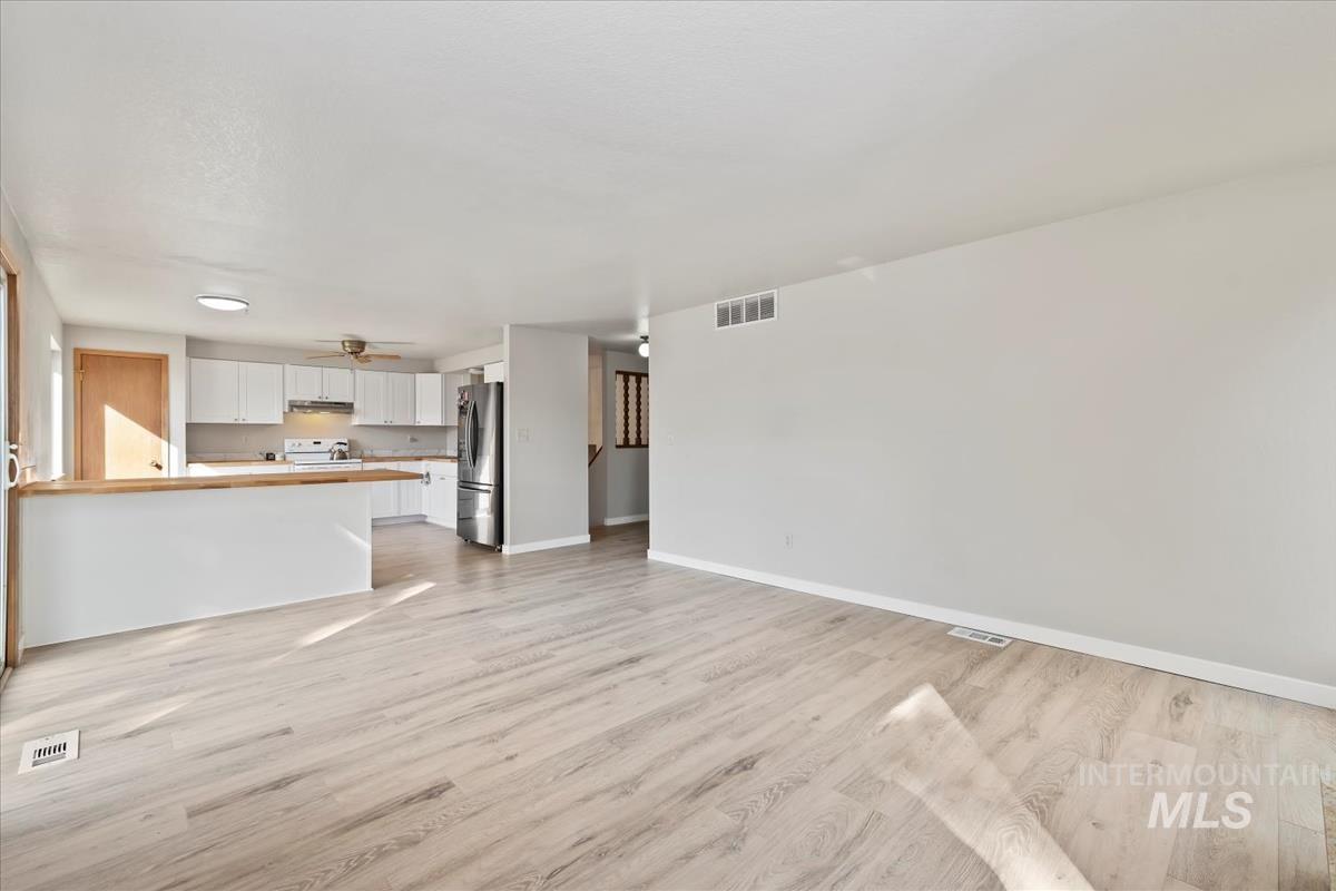 Unfurnished living room featuring light wood-type flooring and a ceiling fan
