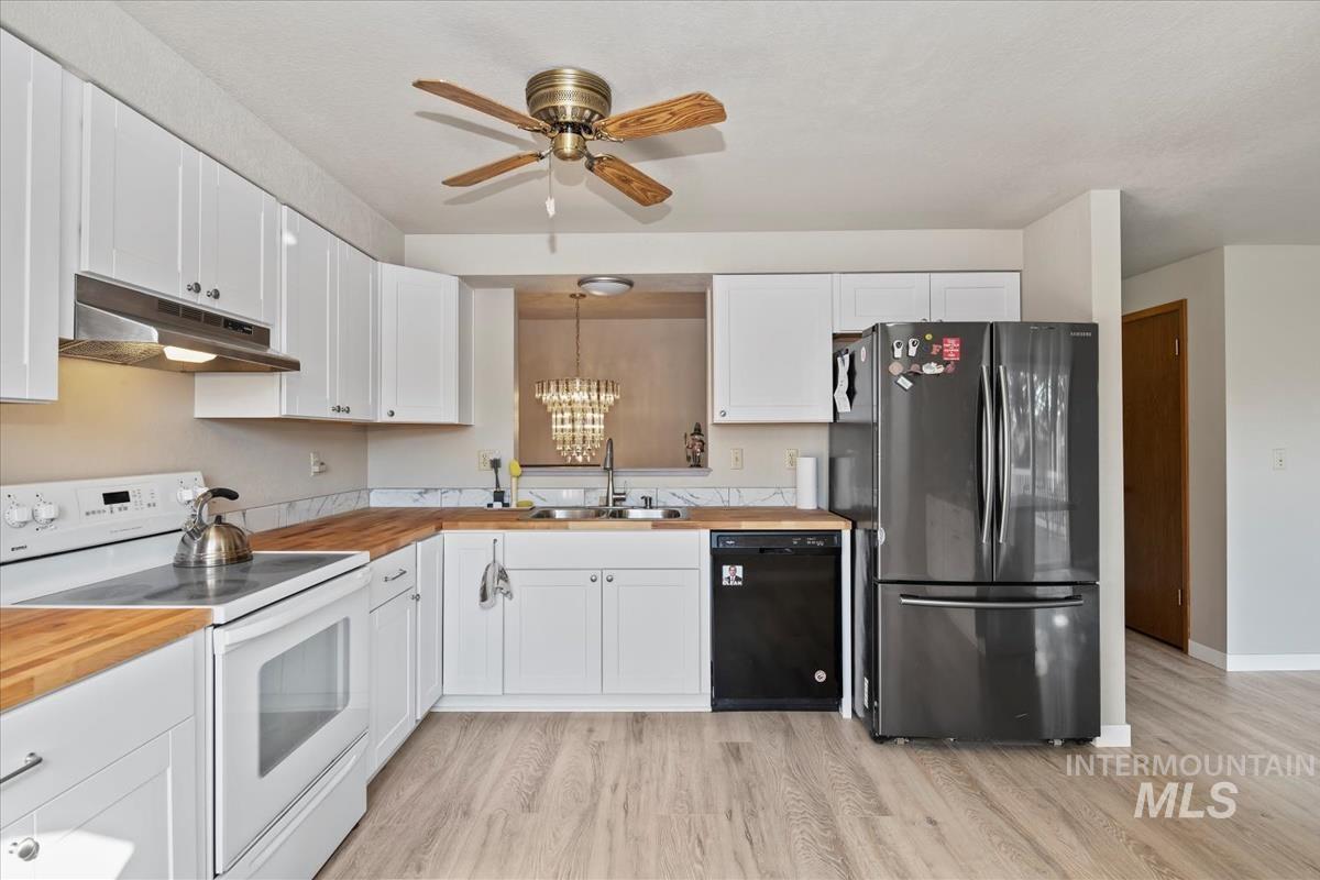 Kitchen with white range with electric stovetop, freestanding refrigerator, black dishwasher, white cabinetry, and under cabinet range hood