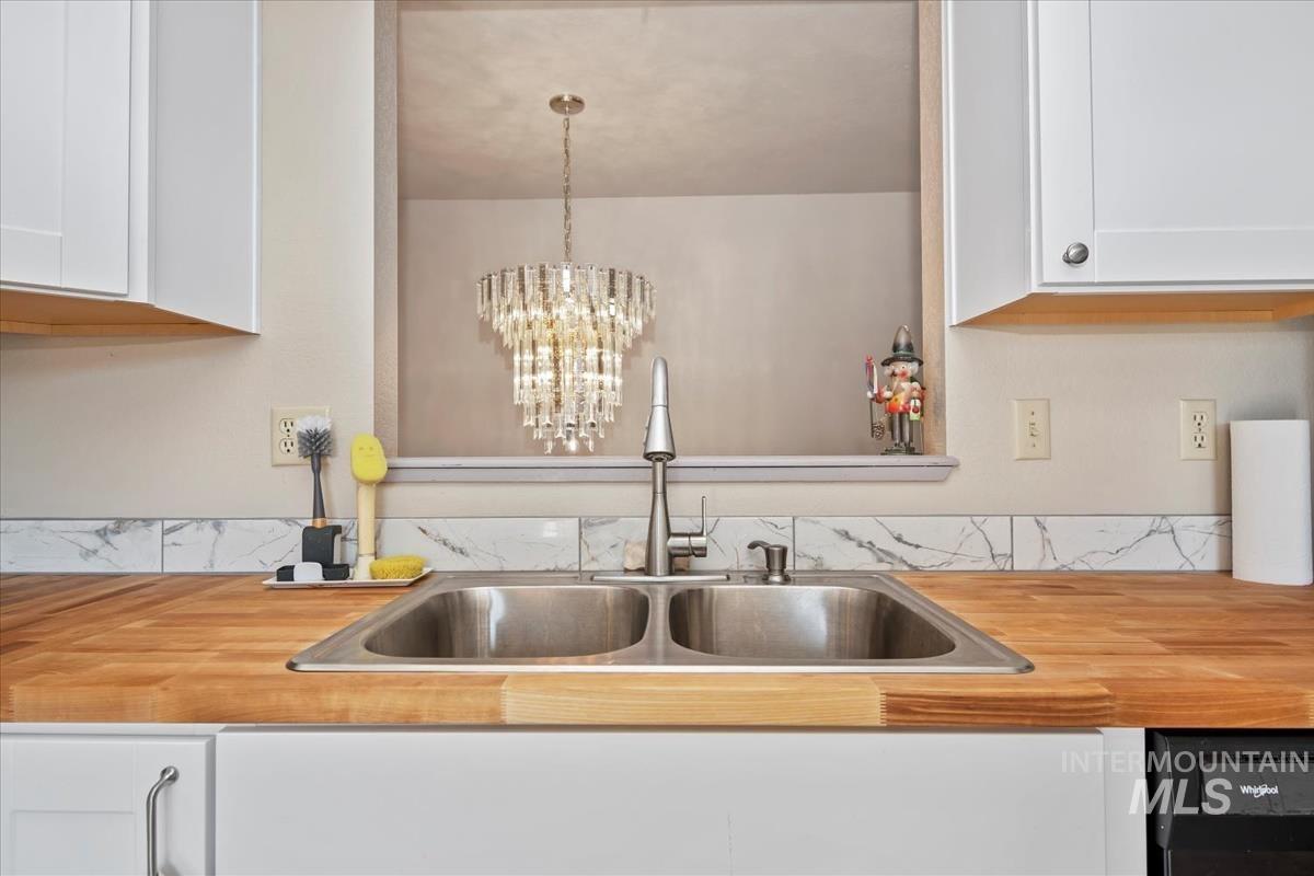 Kitchen featuring white cabinets, a chandelier, and wooden counters