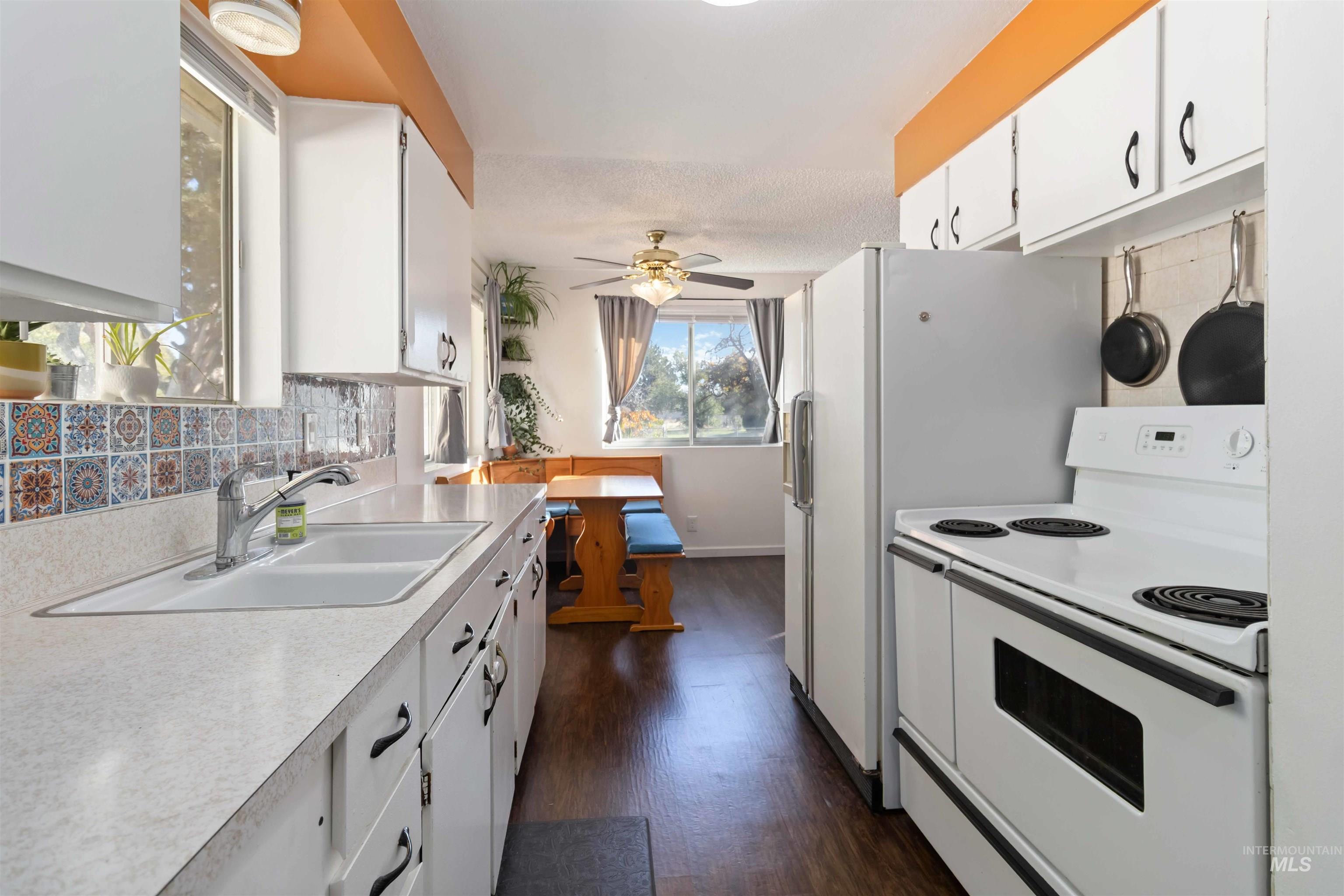 Kitchen with white cabinetry, white appliances, light countertops, dark wood finished floors, and ceiling fan