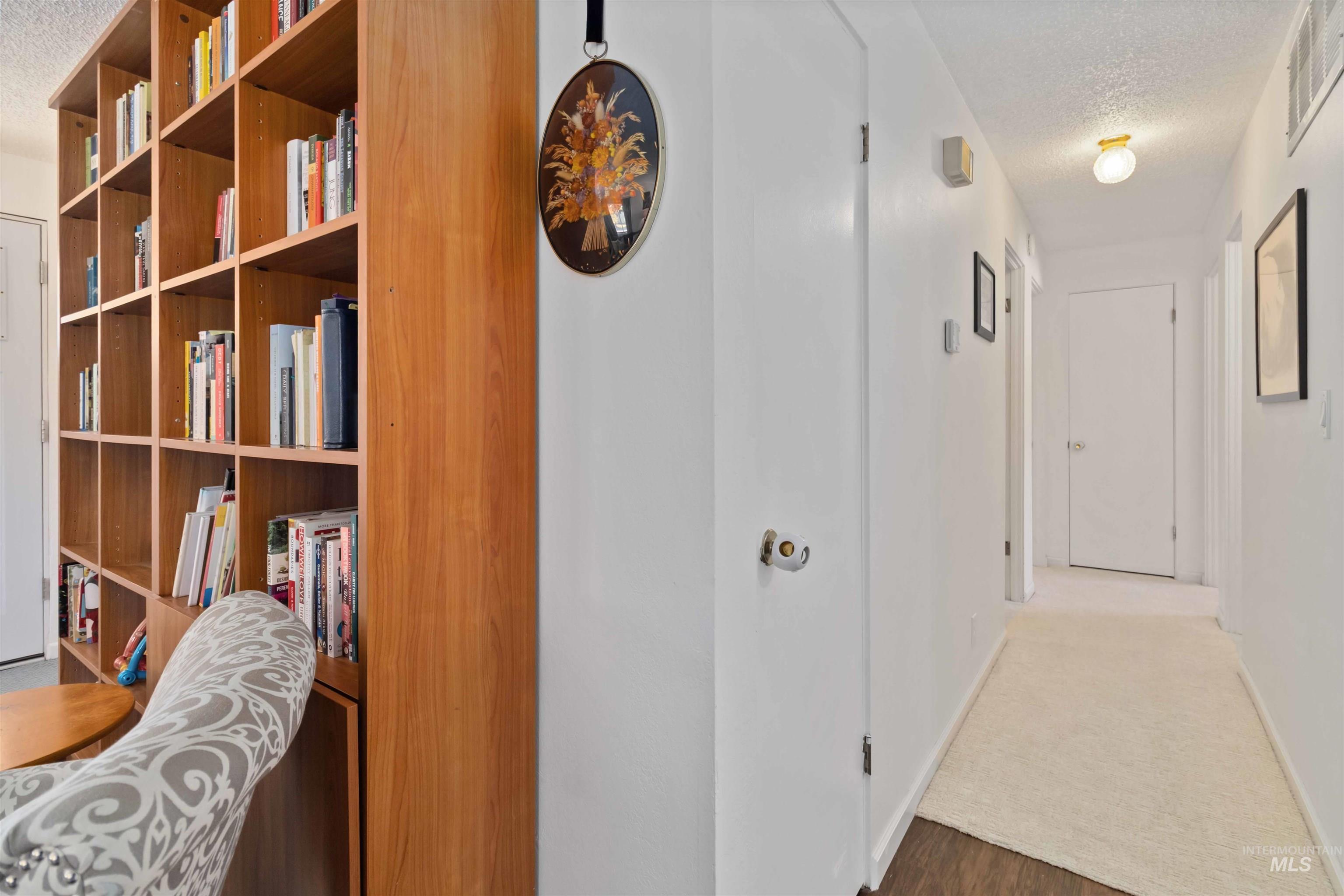 Corridor featuring a textured ceiling and wood finished floors