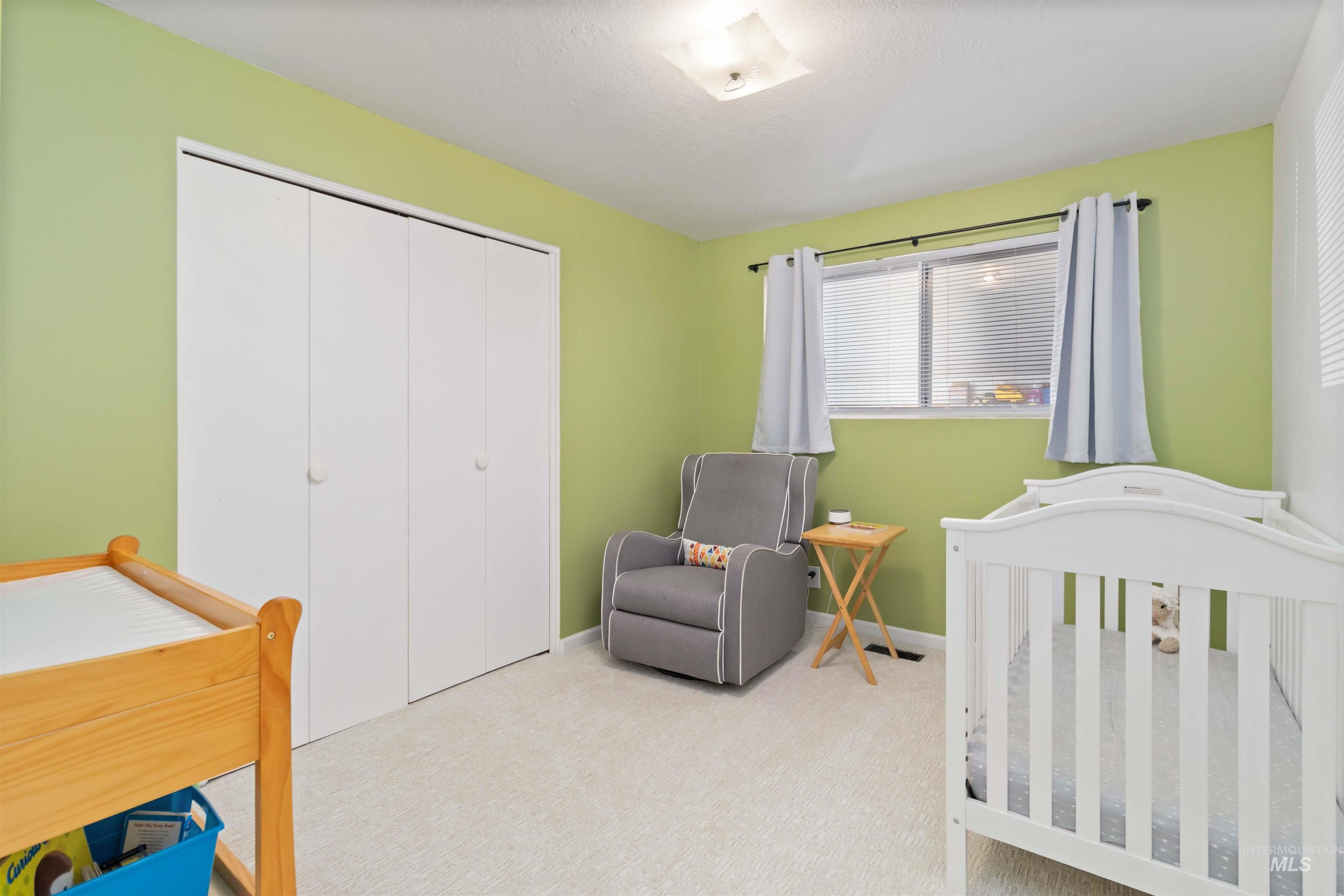 Bedroom with carpet flooring, a closet, and a nursery area