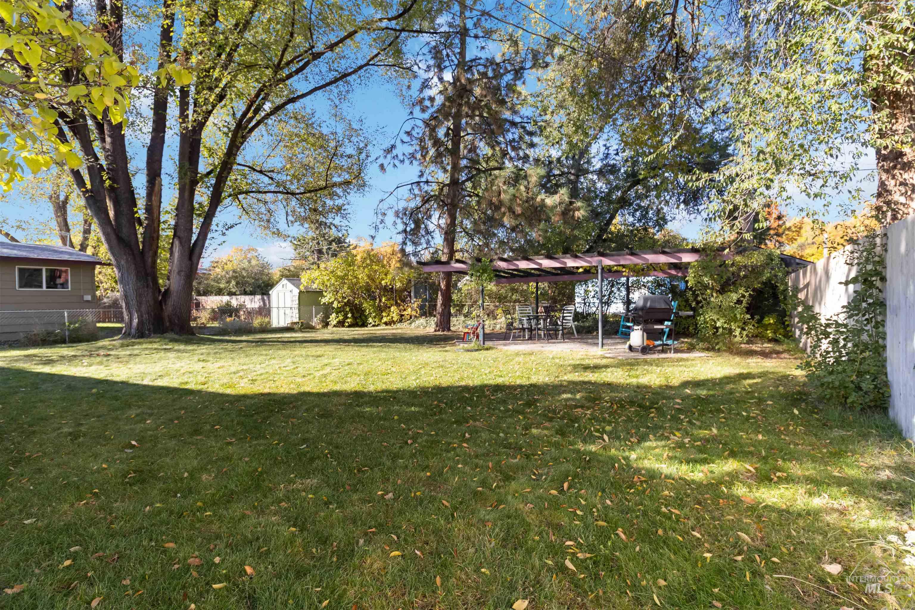Fenced backyard featuring a storage shed and a patio area