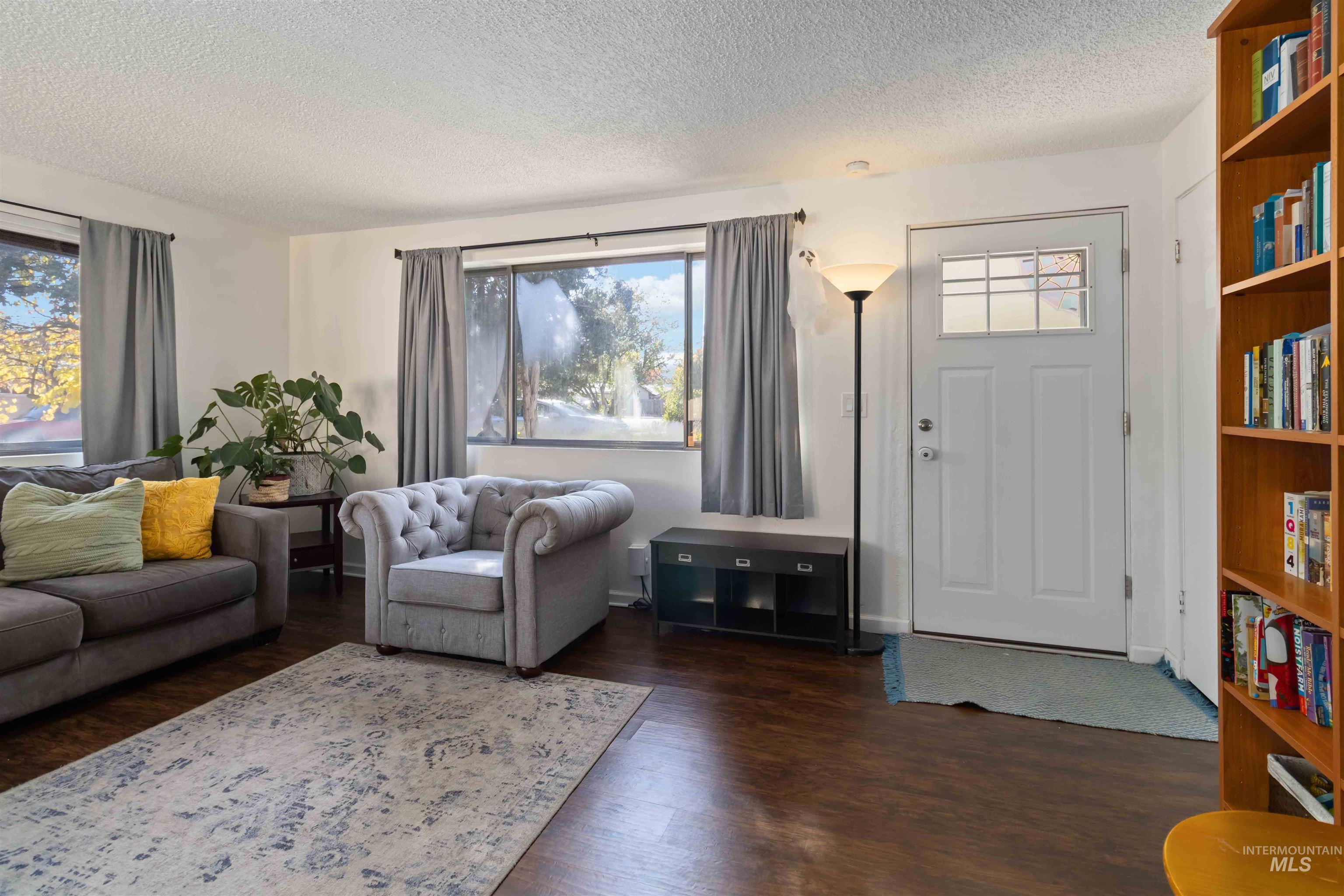 Living area with a textured ceiling and dark wood-style floors
