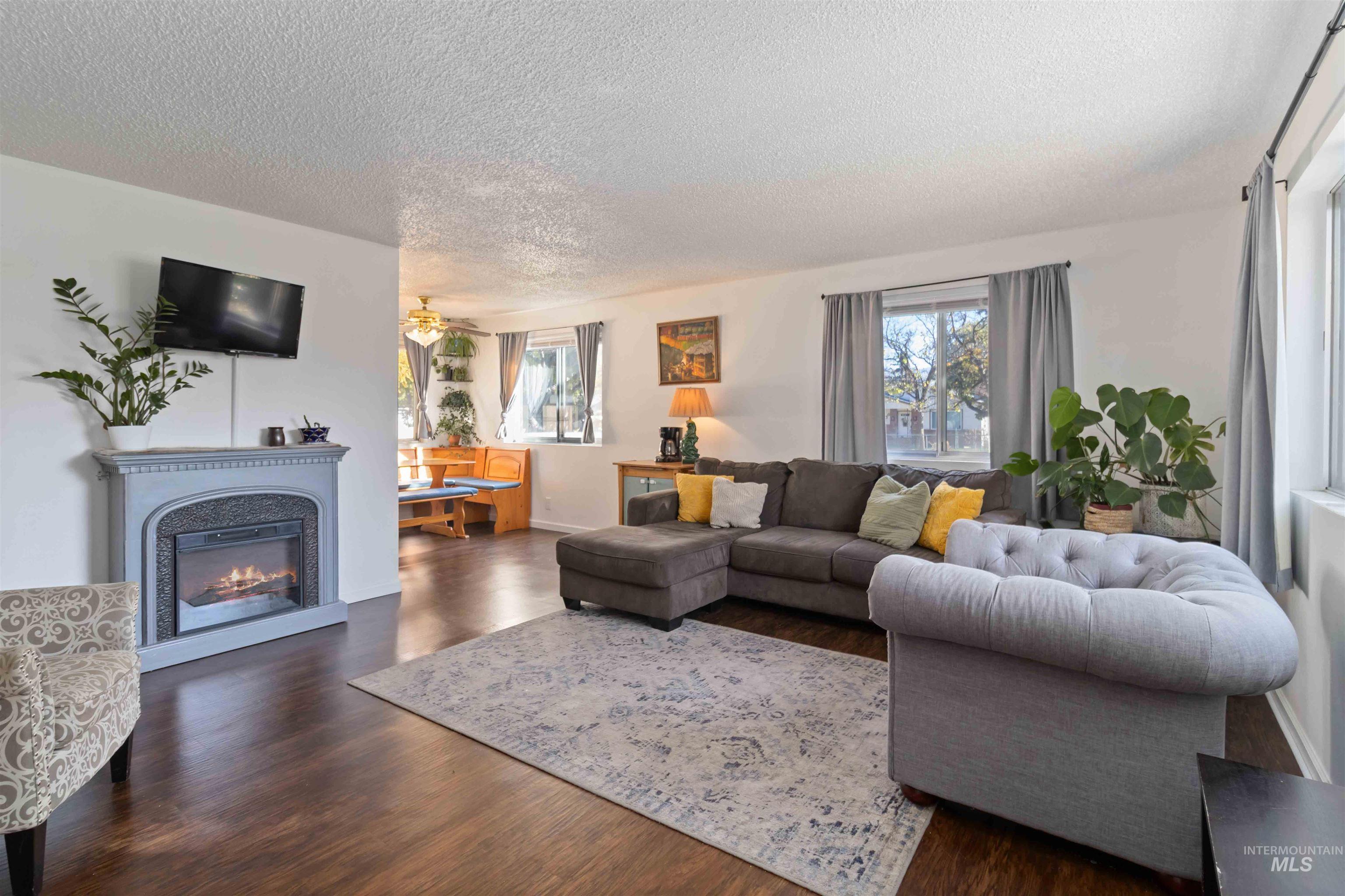 Living room with dark wood-style floors, a glass covered fireplace, and a textured ceiling
