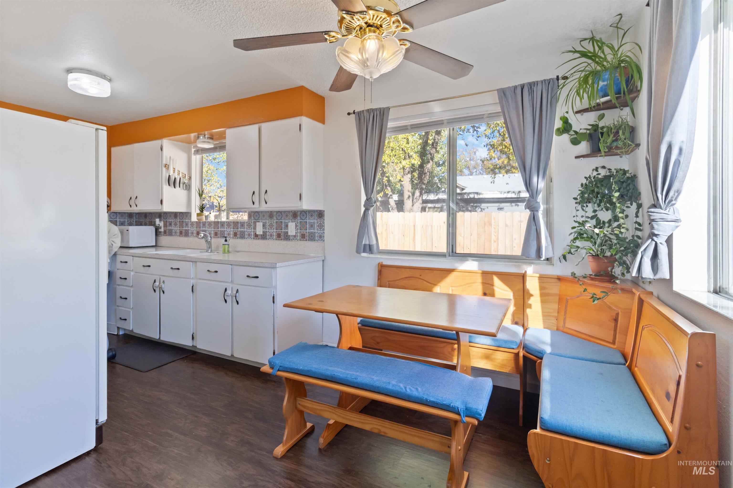 Kitchen featuring light countertops, white appliances, white cabinets, decorative backsplash, and healthy amount of natural light