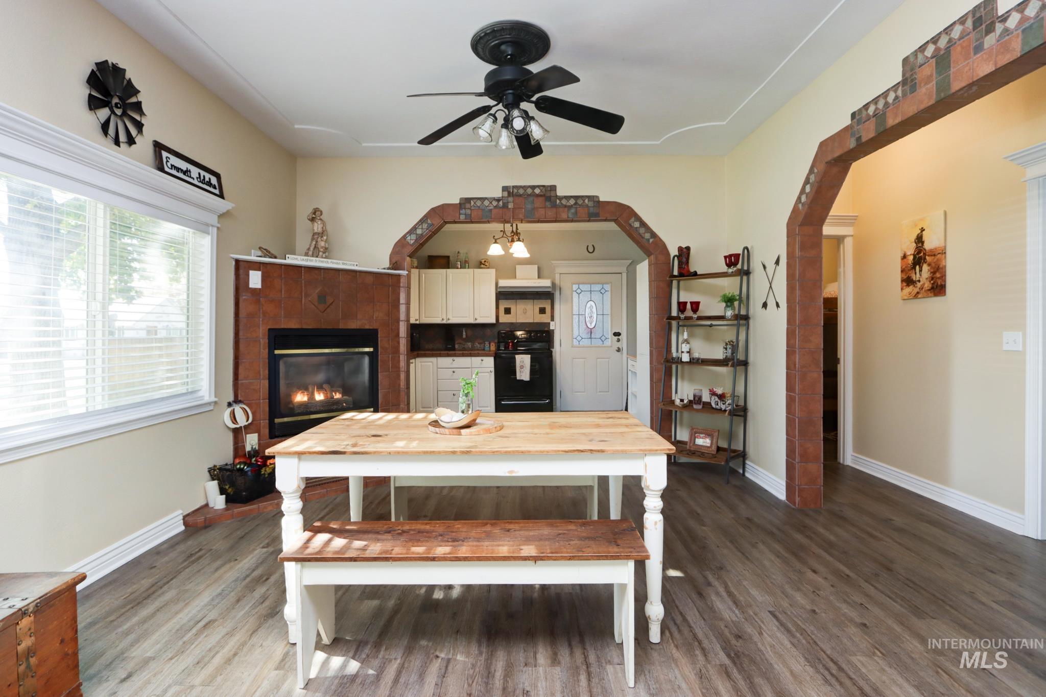 Dining area with wood finished floors, arched walkways, and a tile fireplace
