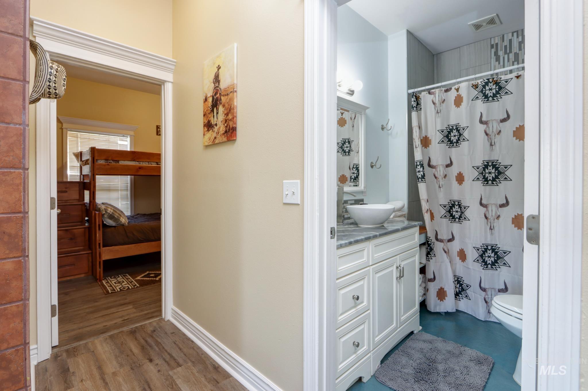 Ensuite bathroom featuring vanity, curtained shower, and dark wood finished floors