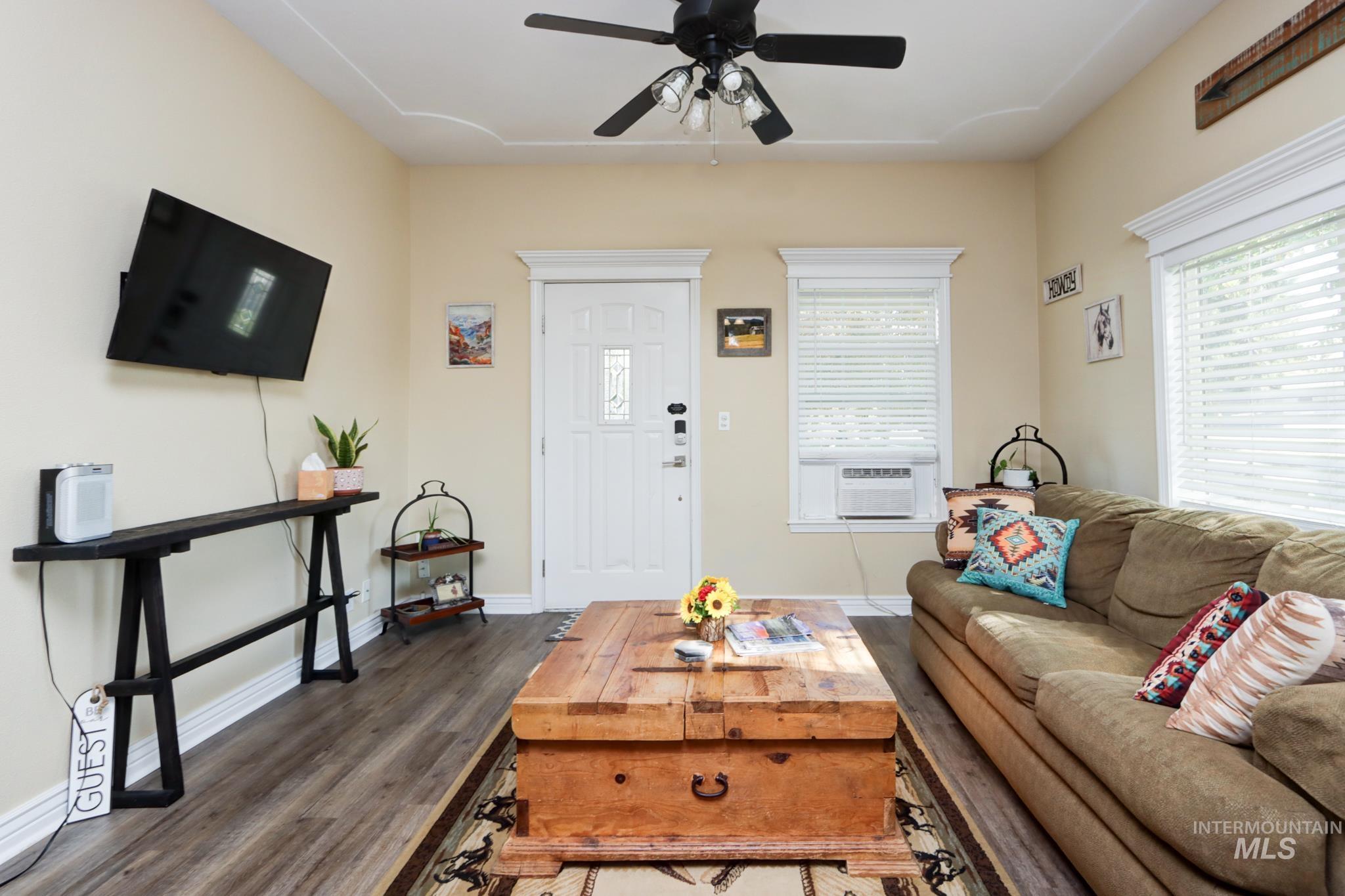 Living room featuring dark wood-style floors, healthy amount of natural light, and a ceiling fan