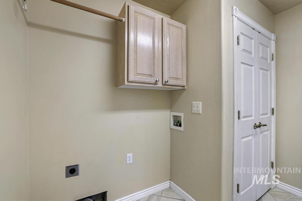 Washroom featuring cabinet space, hookup for a washing machine, light tile patterned floors, and electric dryer hookup