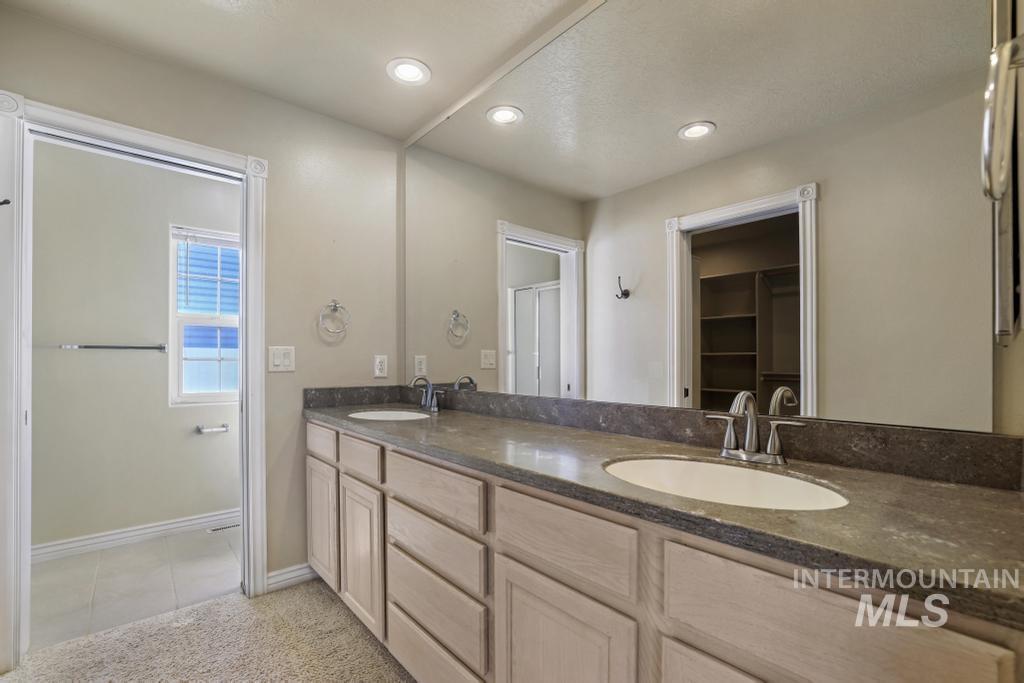 Bathroom with double vanity, light tile patterned floors, recessed lighting, a walk in closet, and light carpet