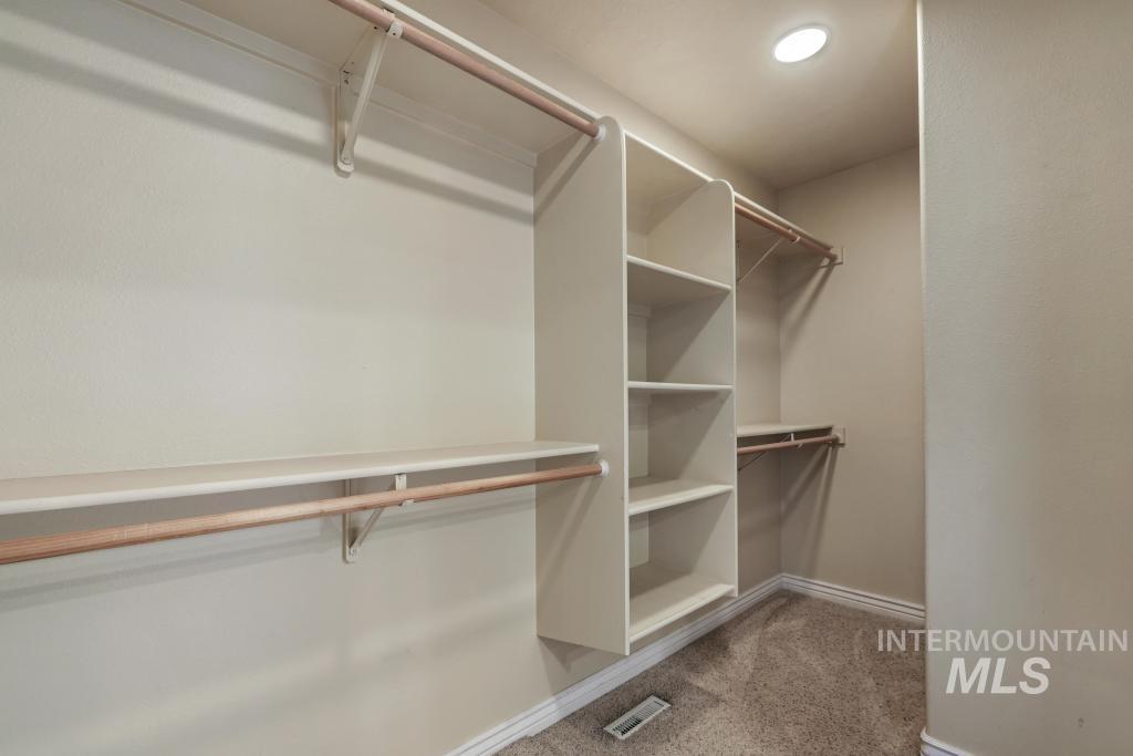 Walk in closet featuring light colored carpet