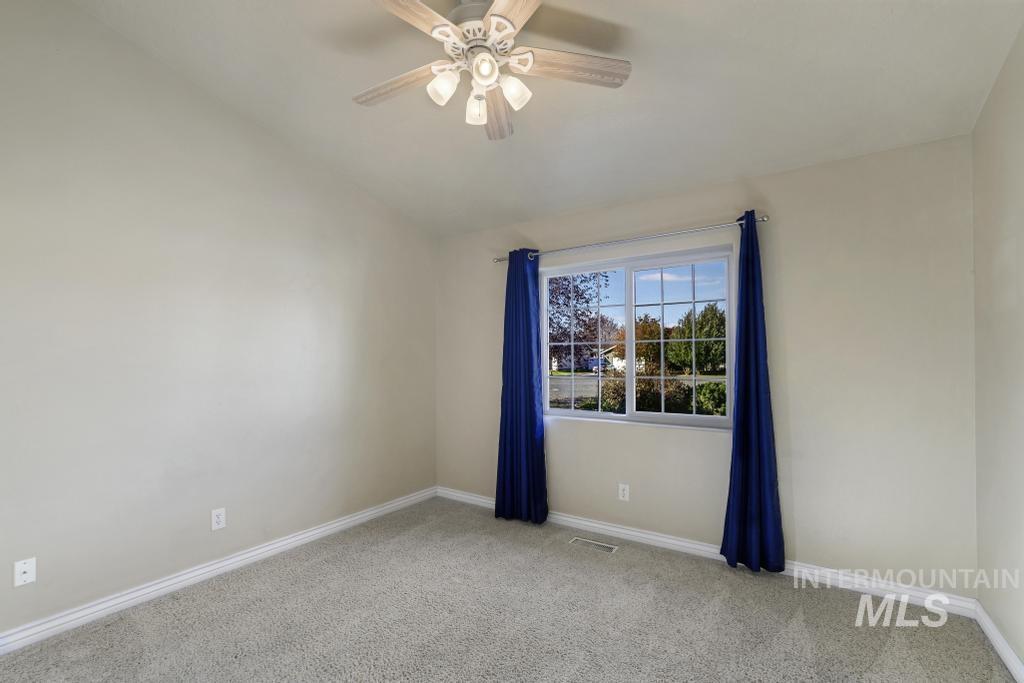 Carpeted spare room featuring baseboards and a ceiling fan