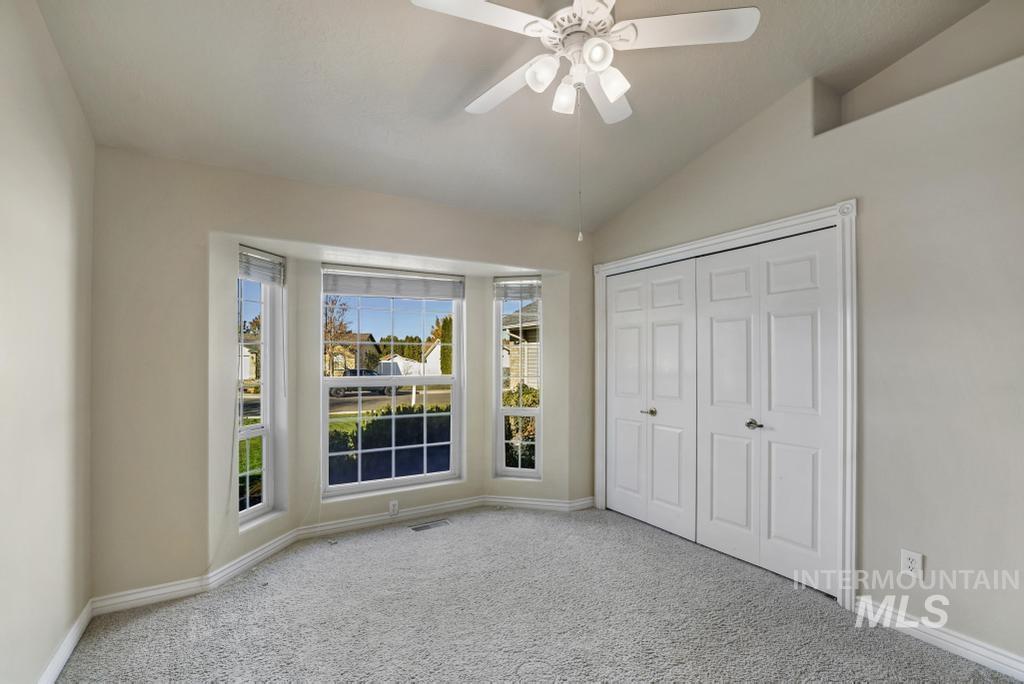 Unfurnished bedroom with carpet floors, ceiling fan, vaulted ceiling, and a closet