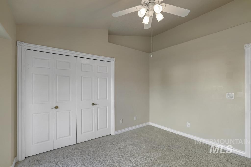 Unfurnished bedroom featuring carpet flooring, a closet, a ceiling fan, and lofted ceiling