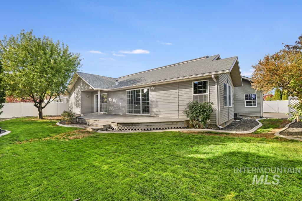 Rear view of house with a fenced backyard, a wooden deck, and a shingled roof
