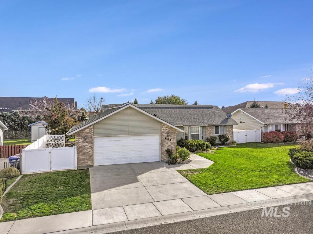 View of front facade with a gate, brick siding, driveway, and an attached garage