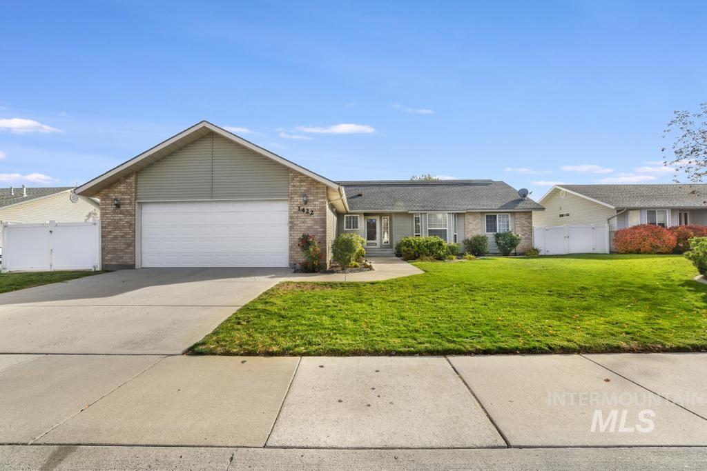Ranch-style house featuring driveway, an attached garage, brick siding, and a gate