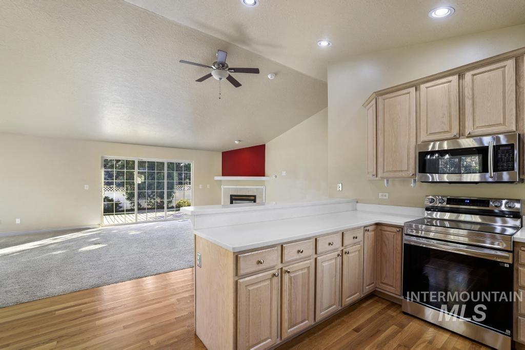 Kitchen featuring lofted ceiling, appliances with stainless steel finishes, open floor plan, light countertops, and a fireplace