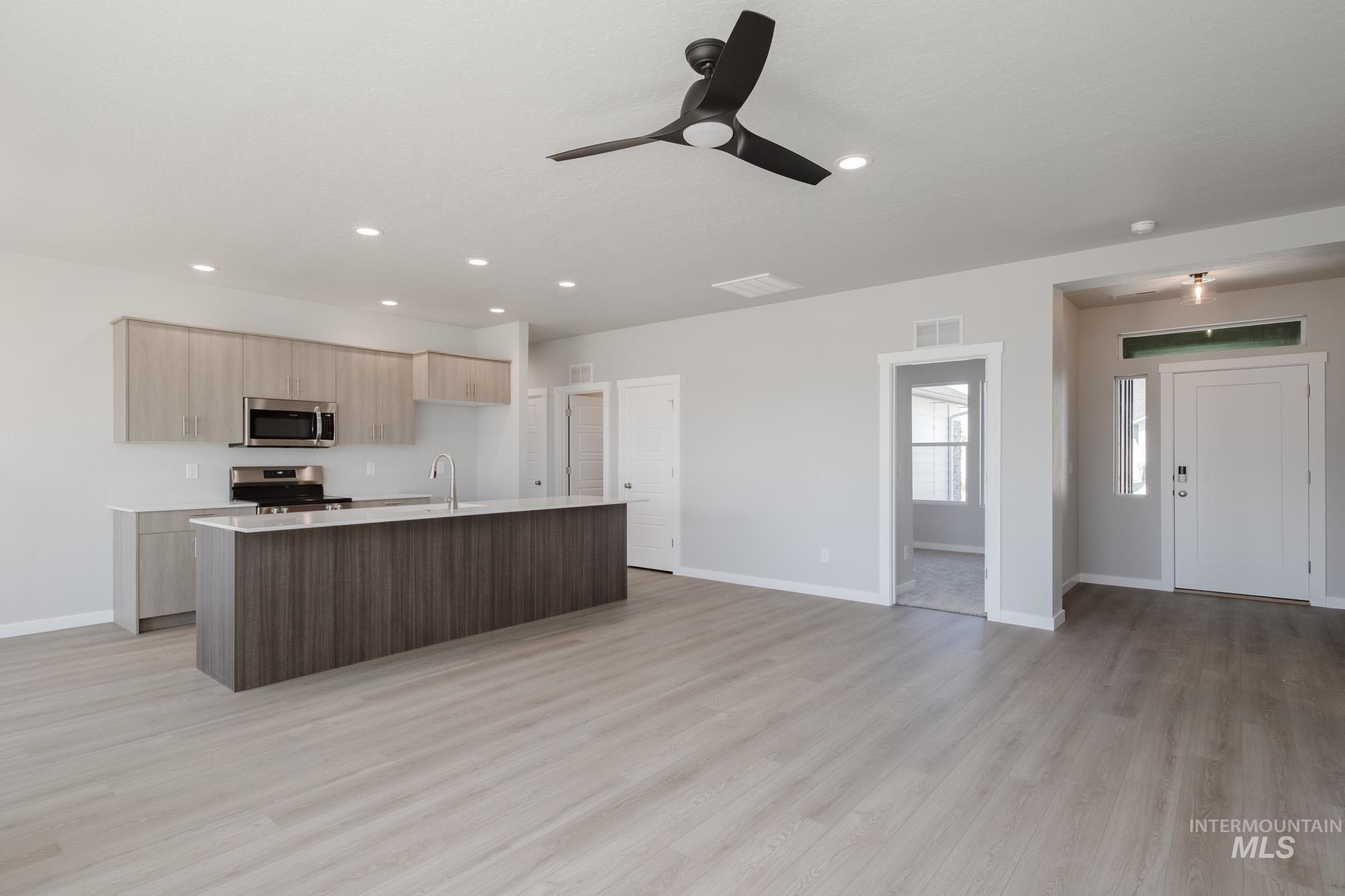 Kitchen with a kitchen island with sink, open floor plan, modern cabinets, stainless steel appliances, and light wood-style flooring