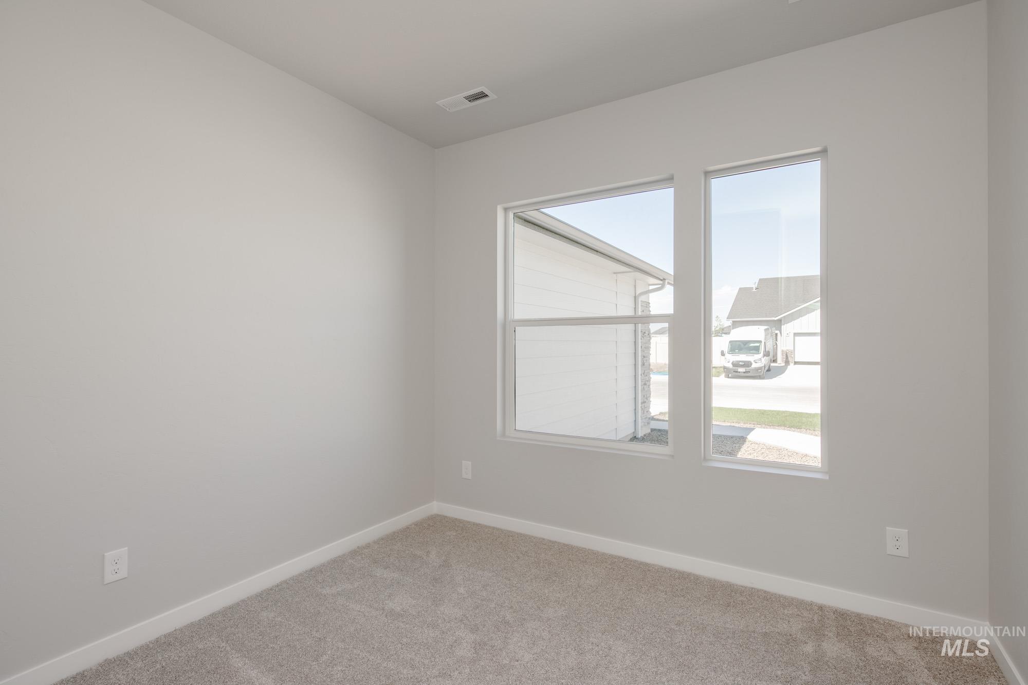 Carpeted spare room featuring baseboards