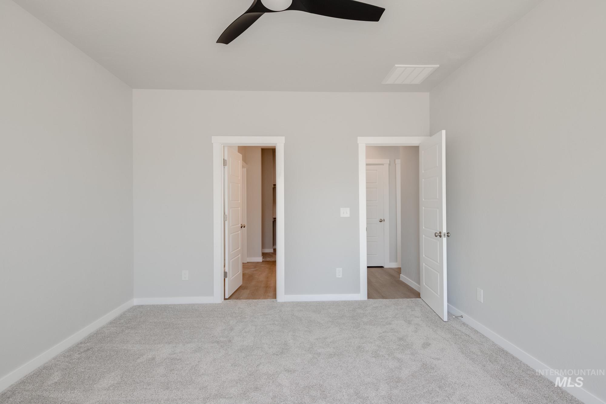 Unfurnished bedroom with light colored carpet and a ceiling fan