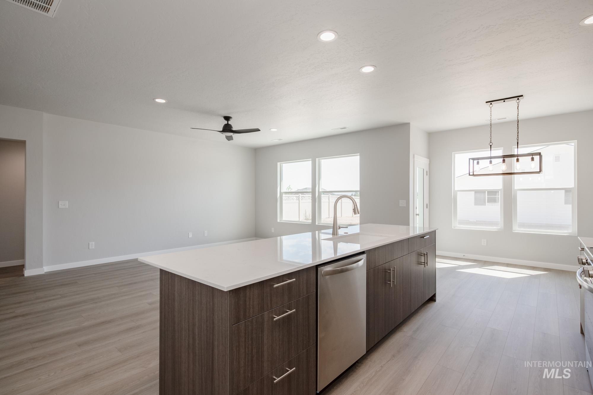 Kitchen with recessed lighting, light wood-type flooring, open floor plan, stainless steel appliances, and dark brown cabinetry