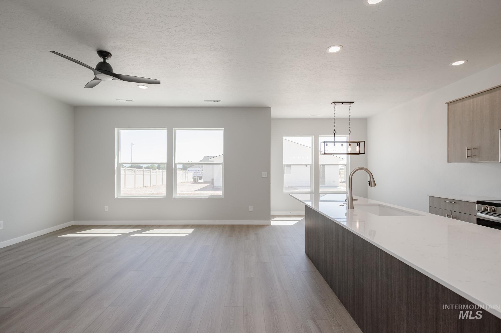 Kitchen featuring hanging light fixtures, light wood-style flooring, modern cabinets, light stone counters, and recessed lighting