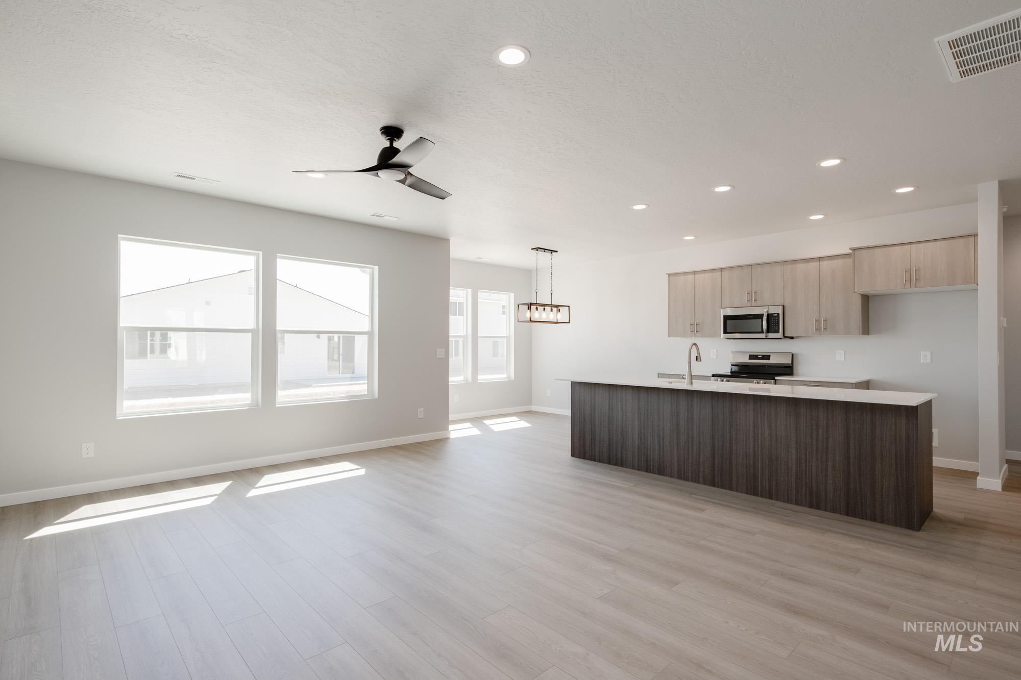 Kitchen featuring open floor plan, an island with sink, appliances with stainless steel finishes, healthy amount of natural light, and recessed lighting