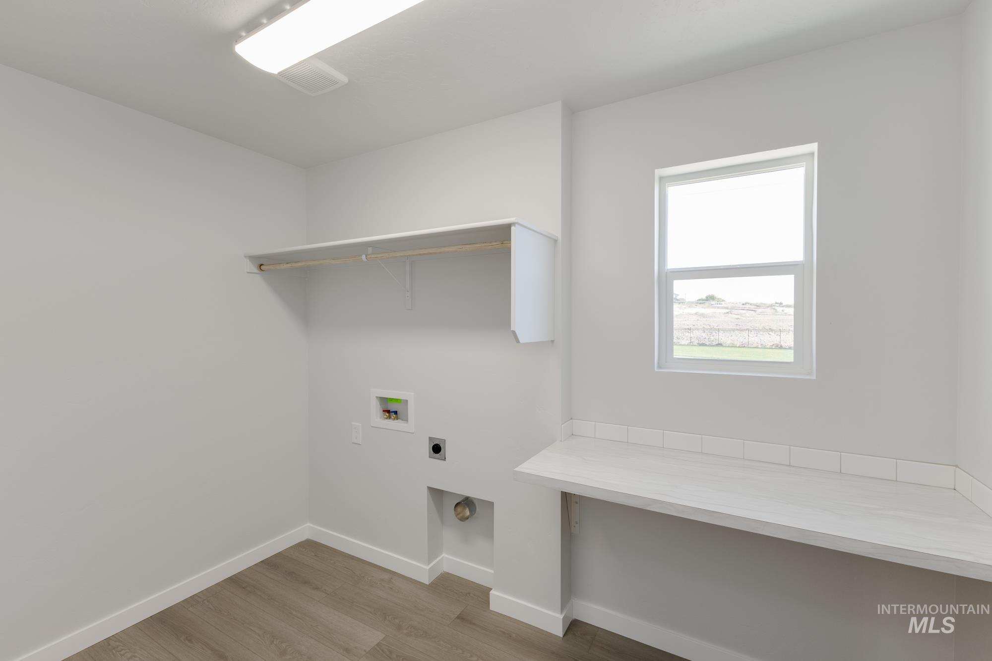 Laundry area with hookup for an electric dryer, light wood-type flooring, and hookup for a washing machine