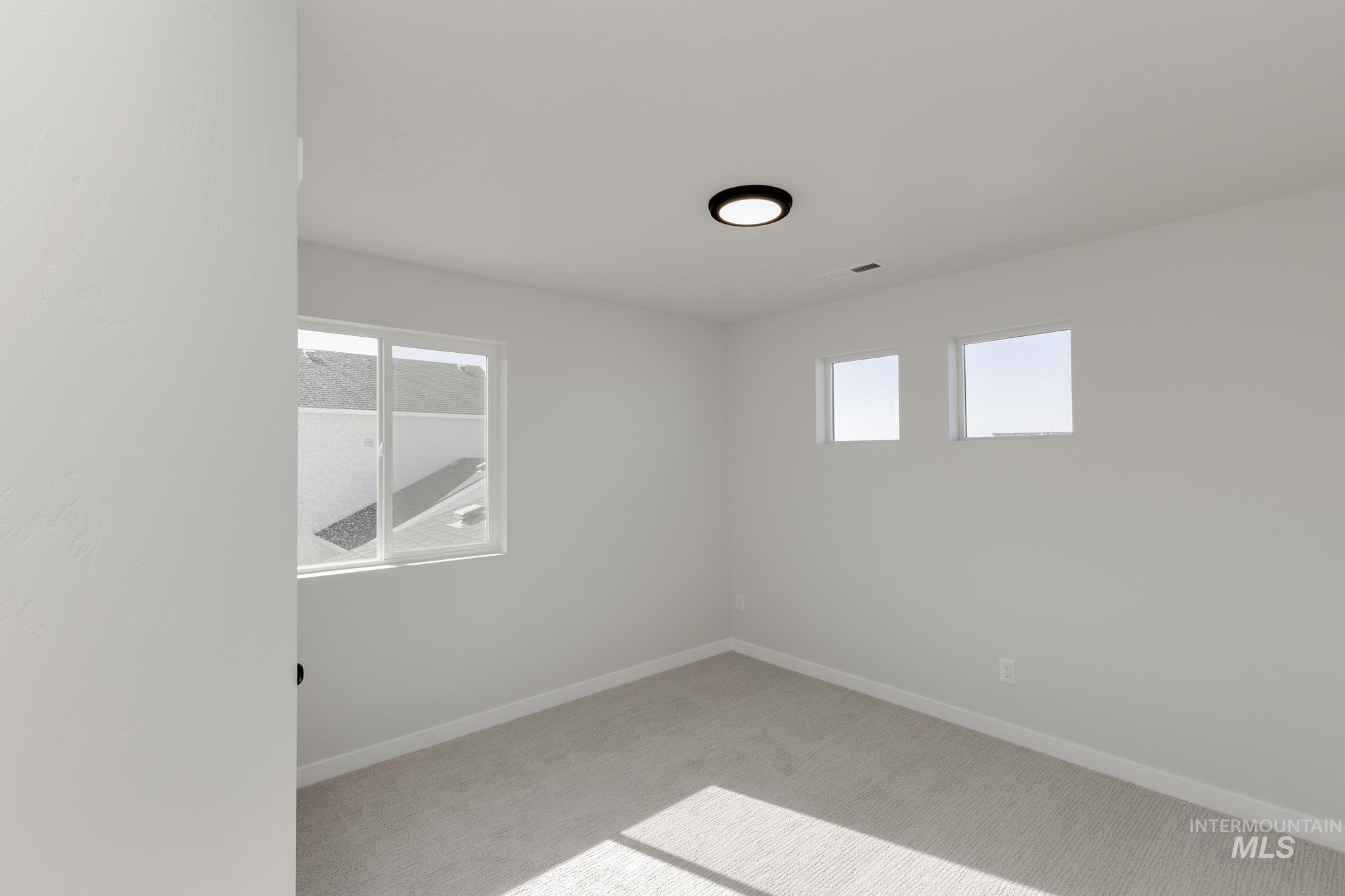 Spare room with light carpet and baseboards