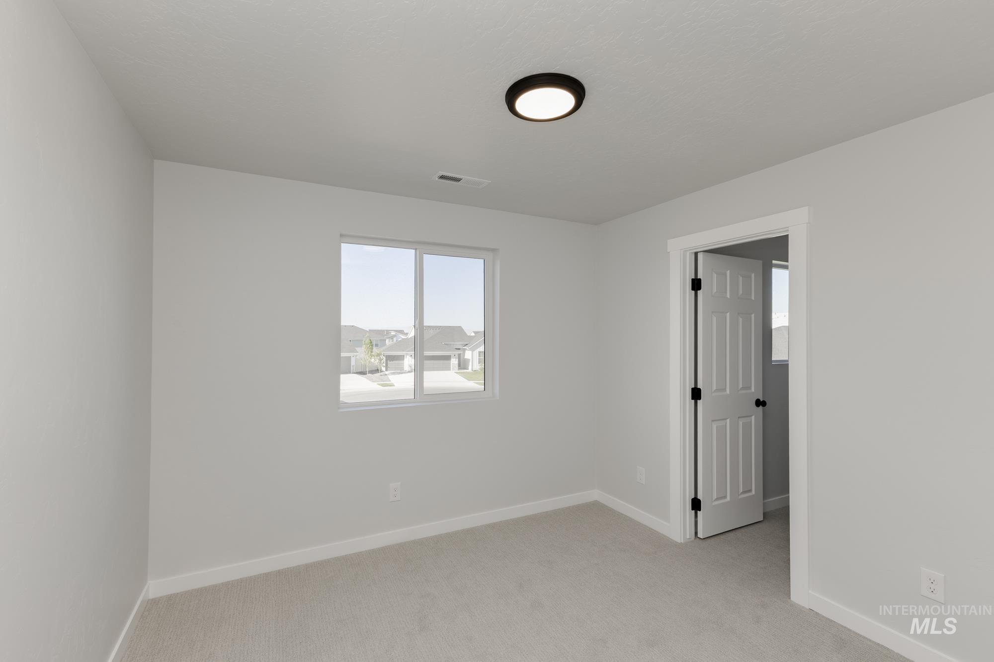 Spare room featuring light carpet and baseboards