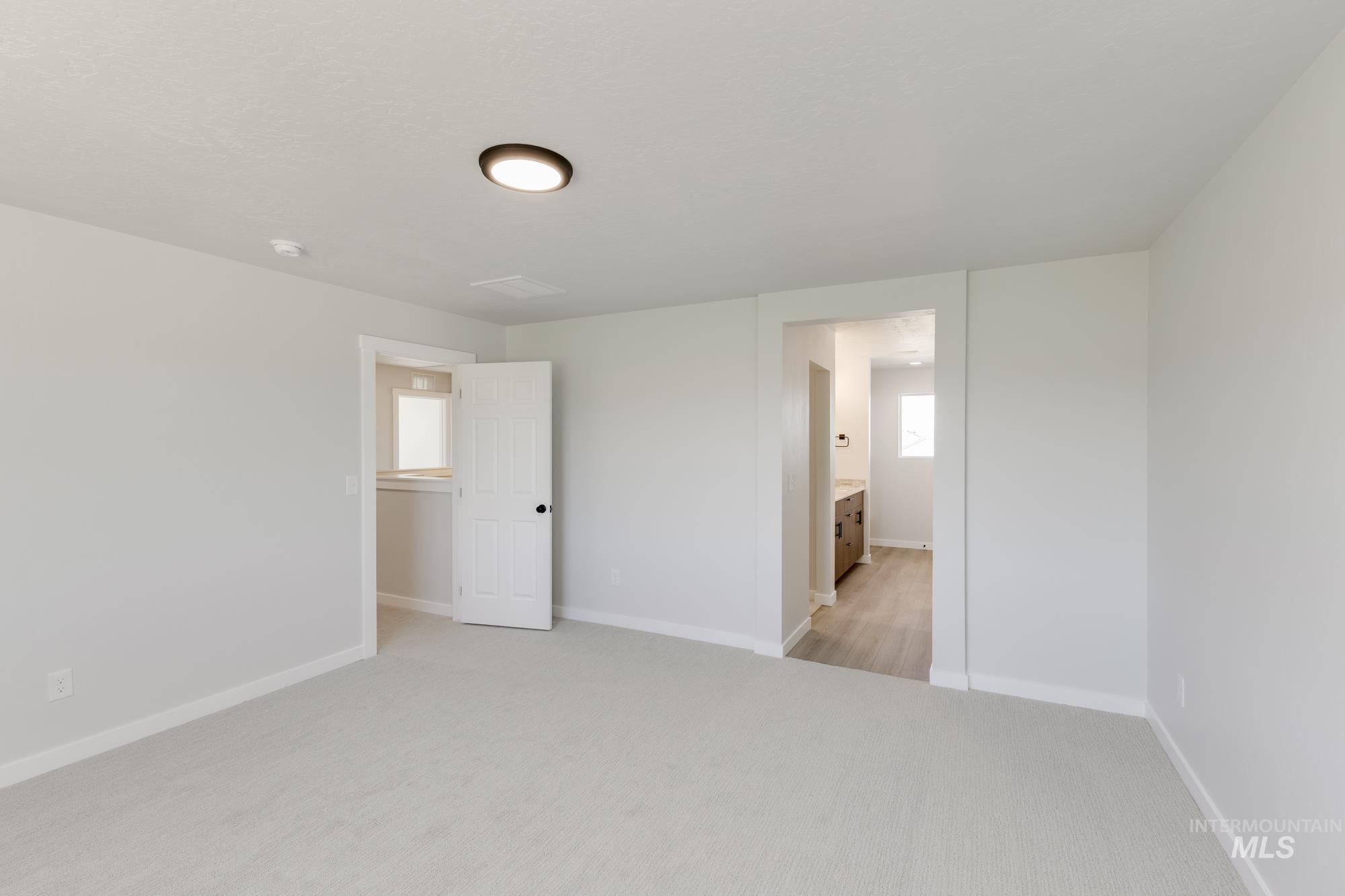 Unfurnished bedroom with light carpet and ensuite bathroom