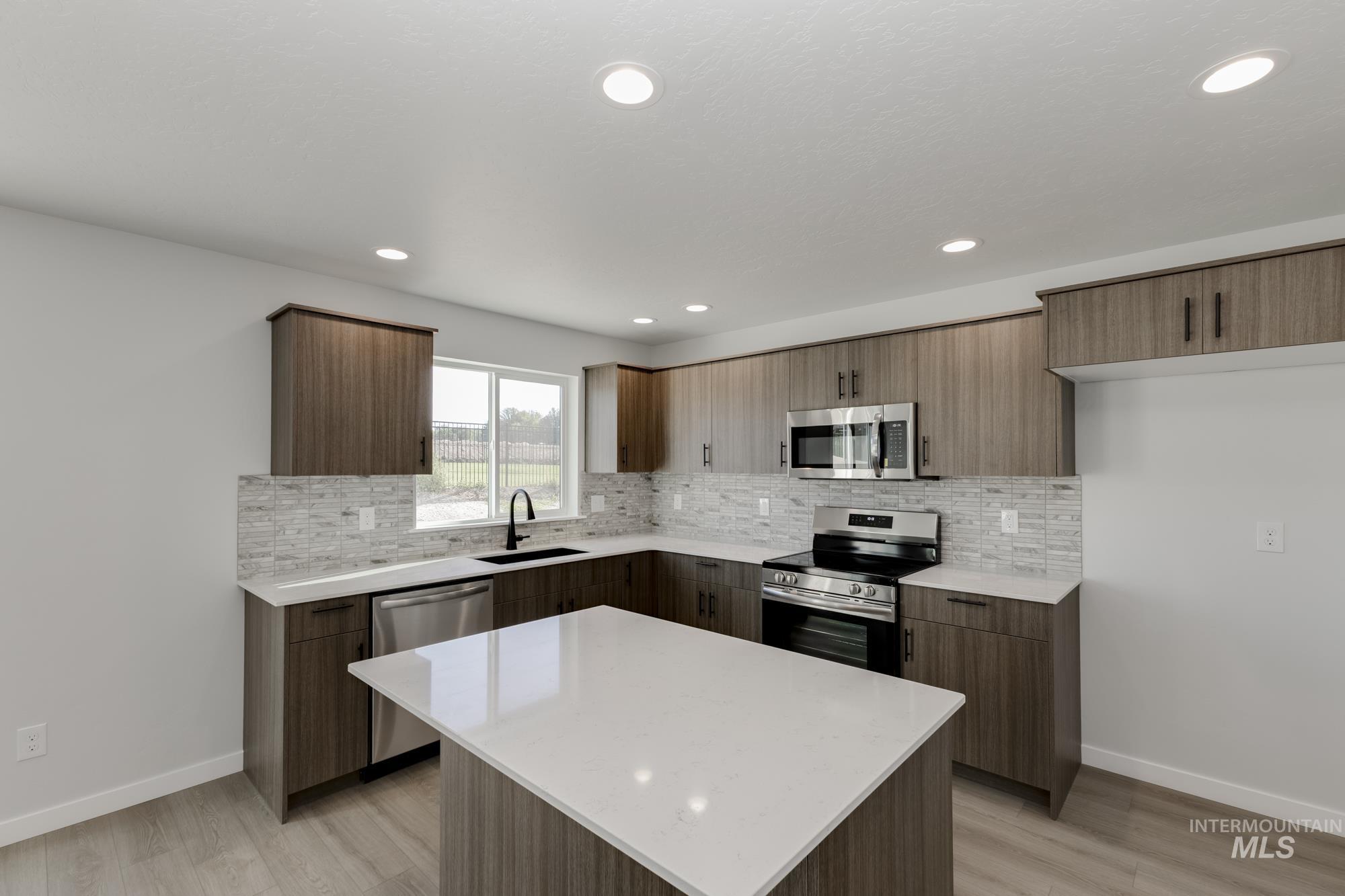 Kitchen with stainless steel appliances, decorative backsplash, light stone counters, light wood finished floors, and recessed lighting
