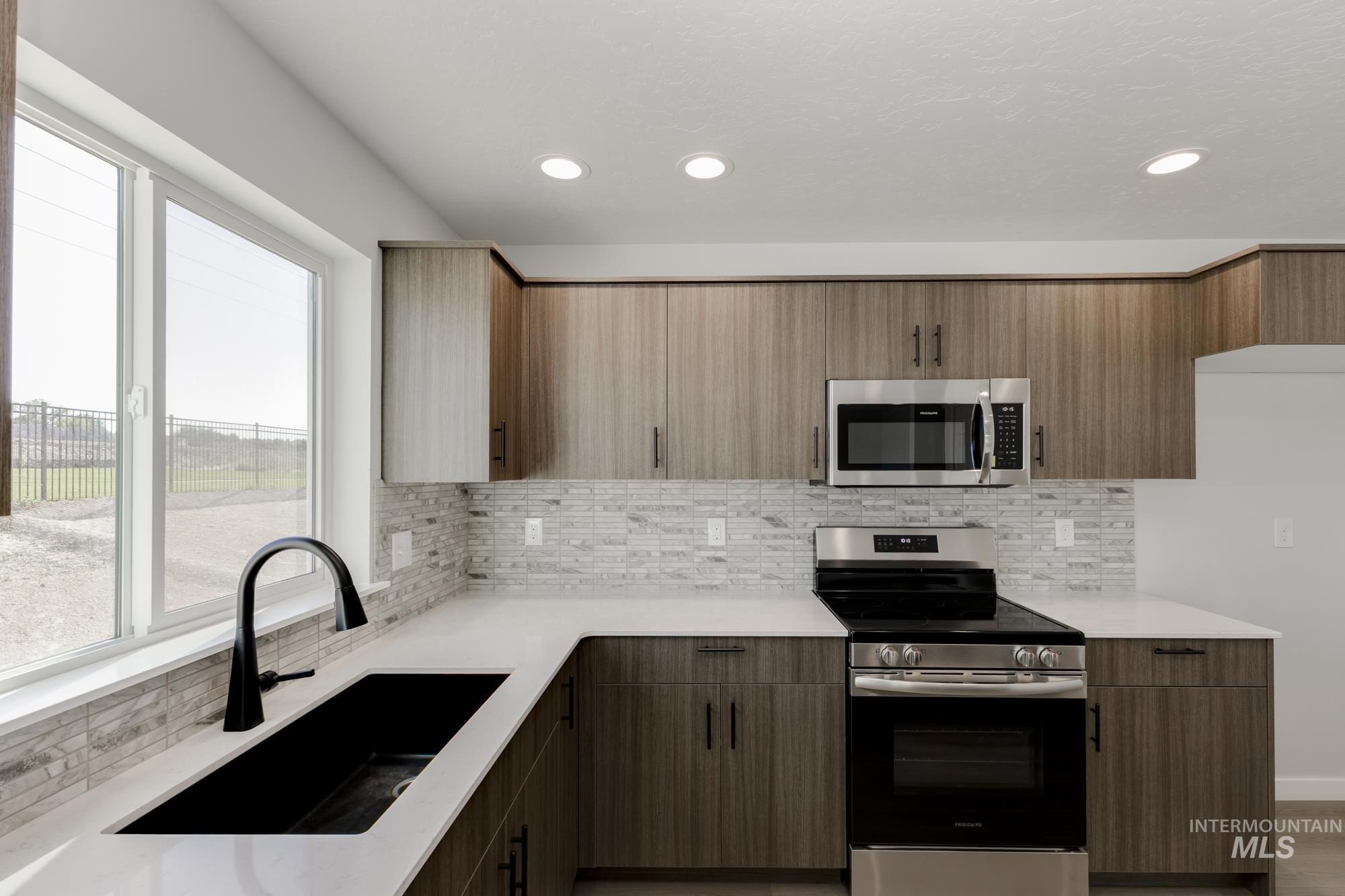 Kitchen with stainless steel appliances, backsplash, light stone countertops, recessed lighting, and modern cabinets