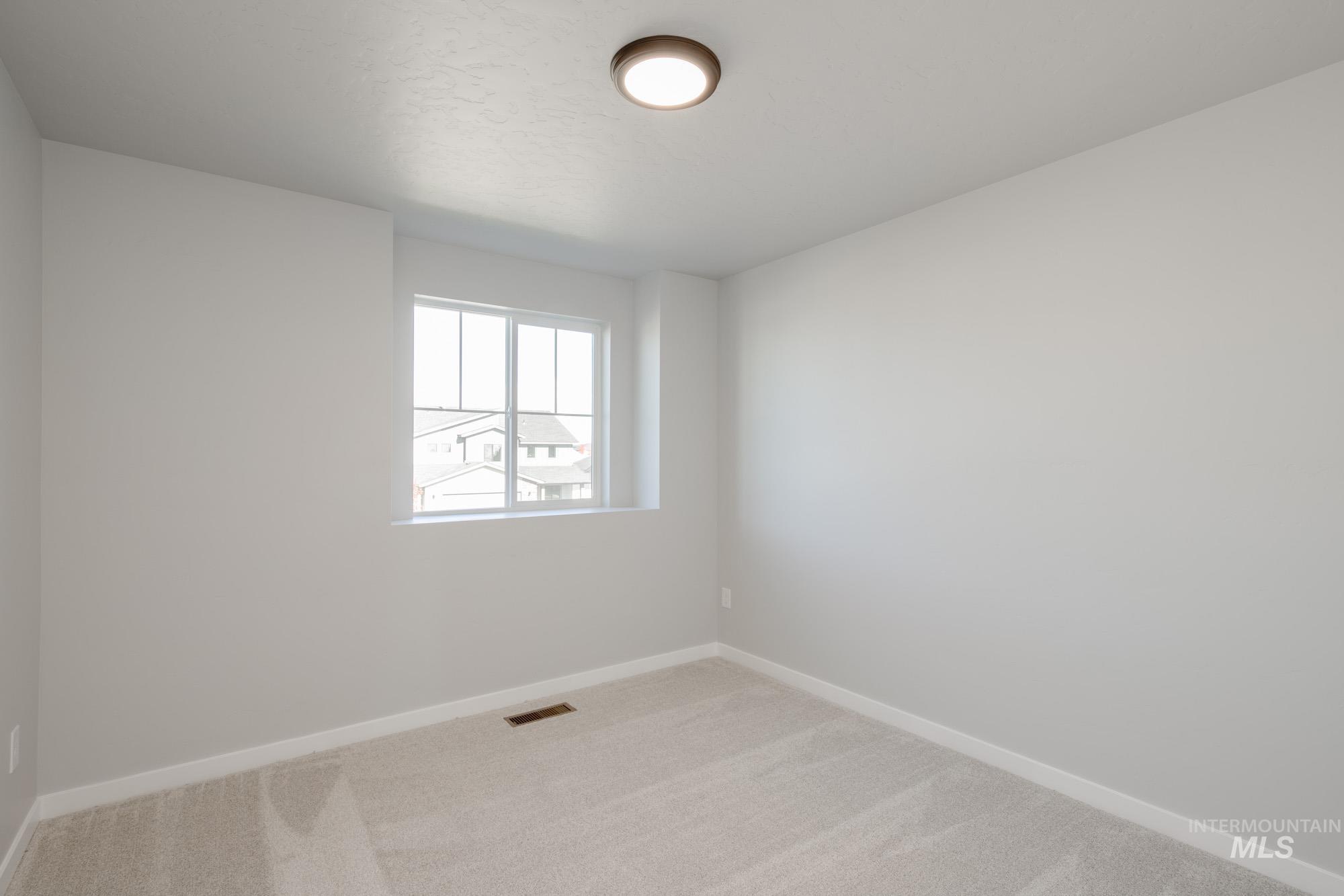 Spare room with baseboards and light carpet