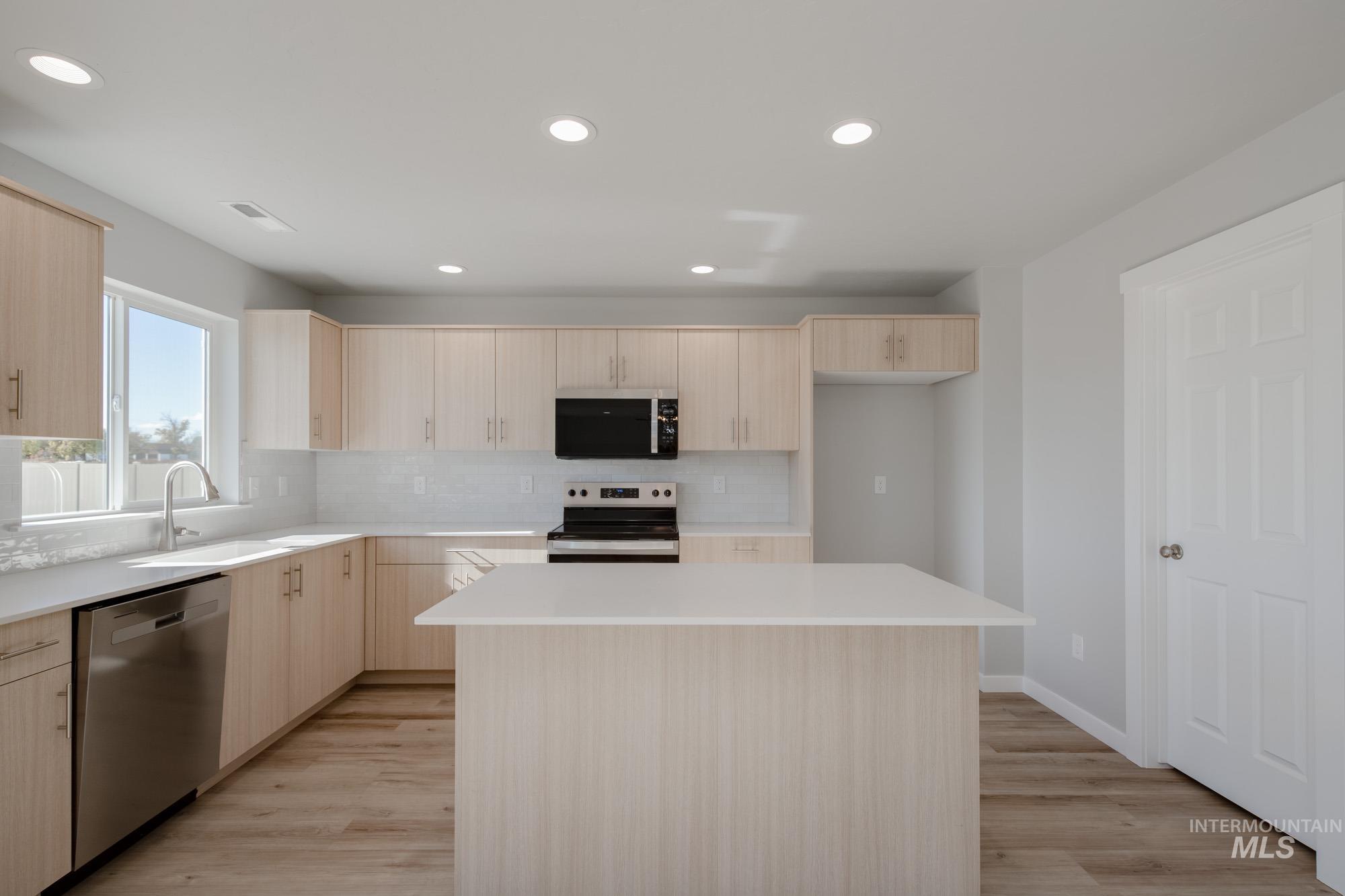 Kitchen featuring light brown cabinets, tasteful backsplash, a center island, stainless steel appliances, and recessed lighting