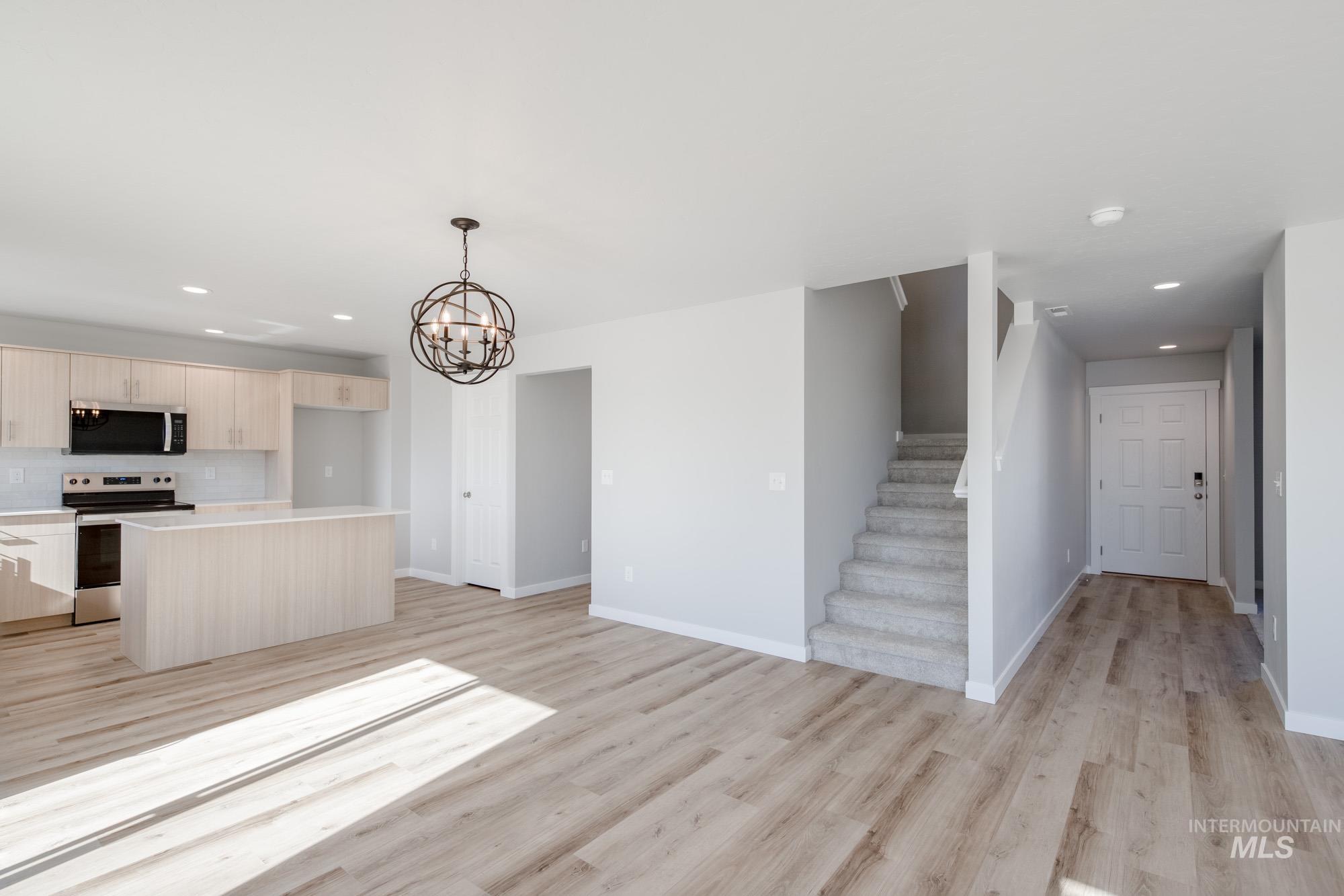 Kitchen with recessed lighting, appliances with stainless steel finishes, hanging light fixtures, a center island, and light wood-style flooring