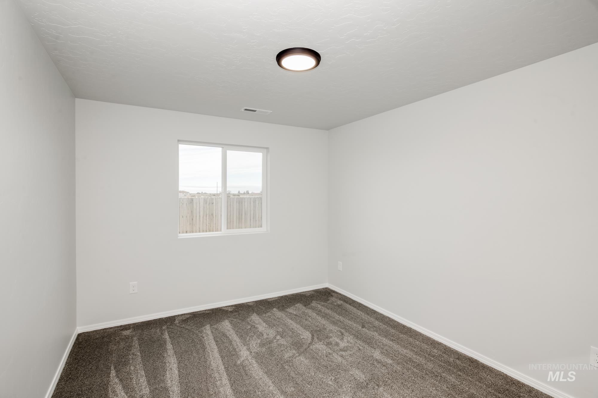 Unfurnished room with dark colored carpet and a textured ceiling