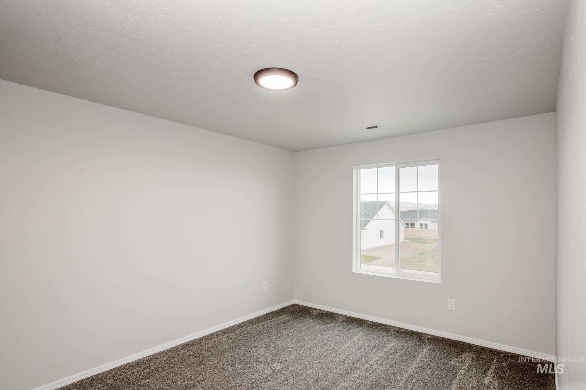 Spare room featuring carpet flooring and baseboards