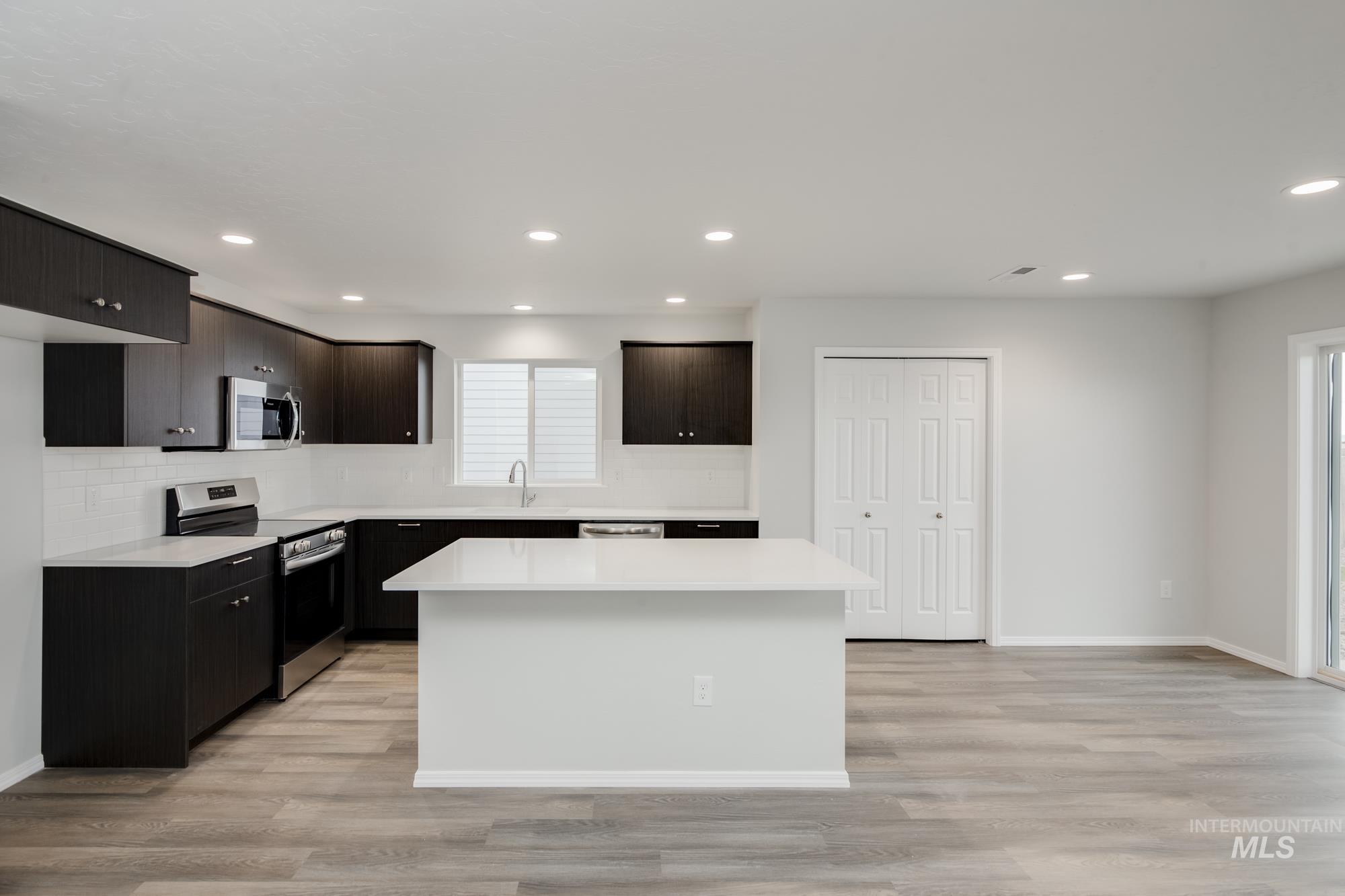 Kitchen featuring stainless steel appliances, a center island, light wood-style floors, recessed lighting, and tasteful backsplash