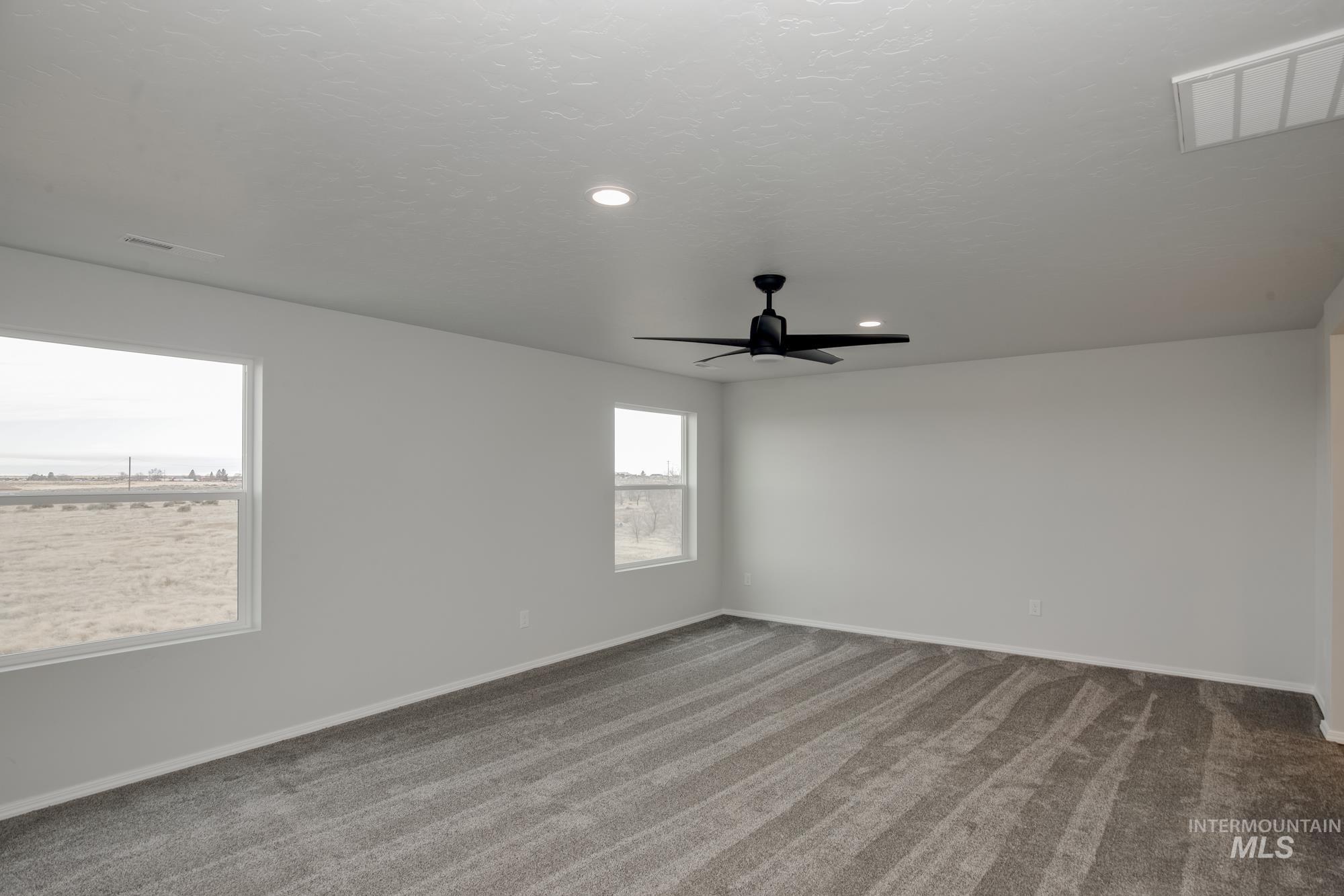 Carpeted empty room with a textured ceiling, recessed lighting, and a ceiling fan
