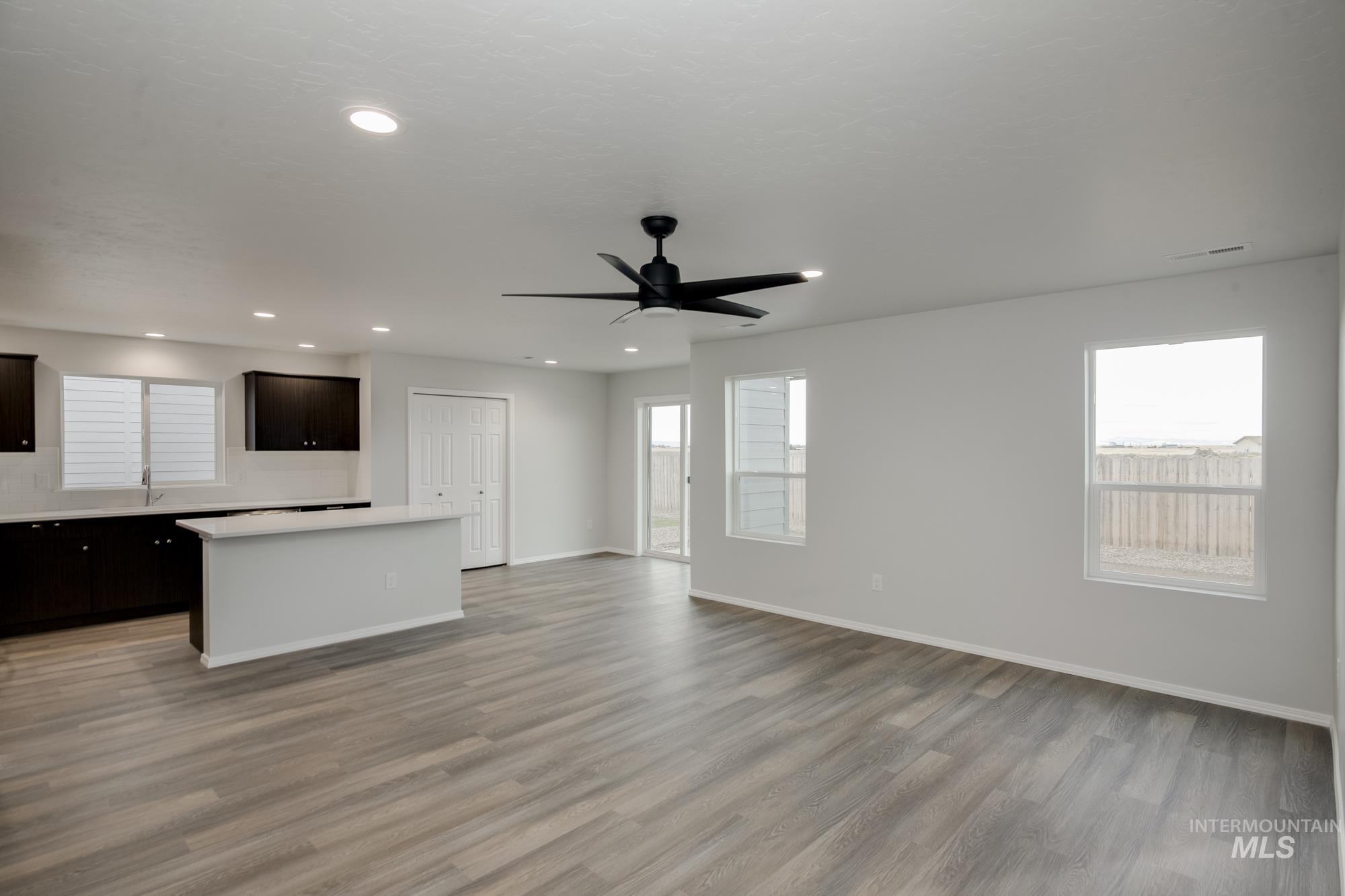Unfurnished living room featuring light wood-style floors, a ceiling fan, and recessed lighting